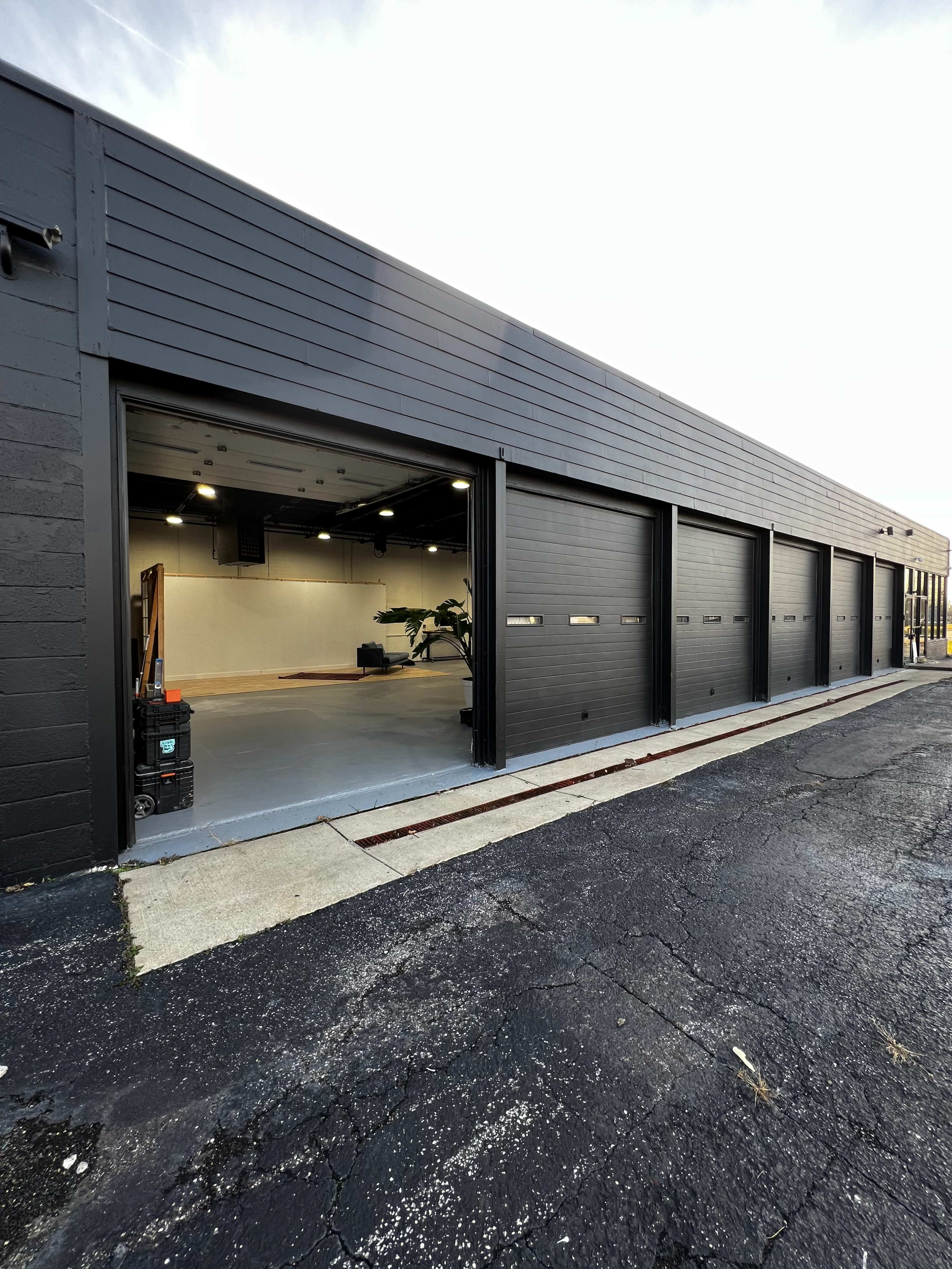 The image shows a modern building with multiple garage doors, featuring a smooth asphalt surface in front.