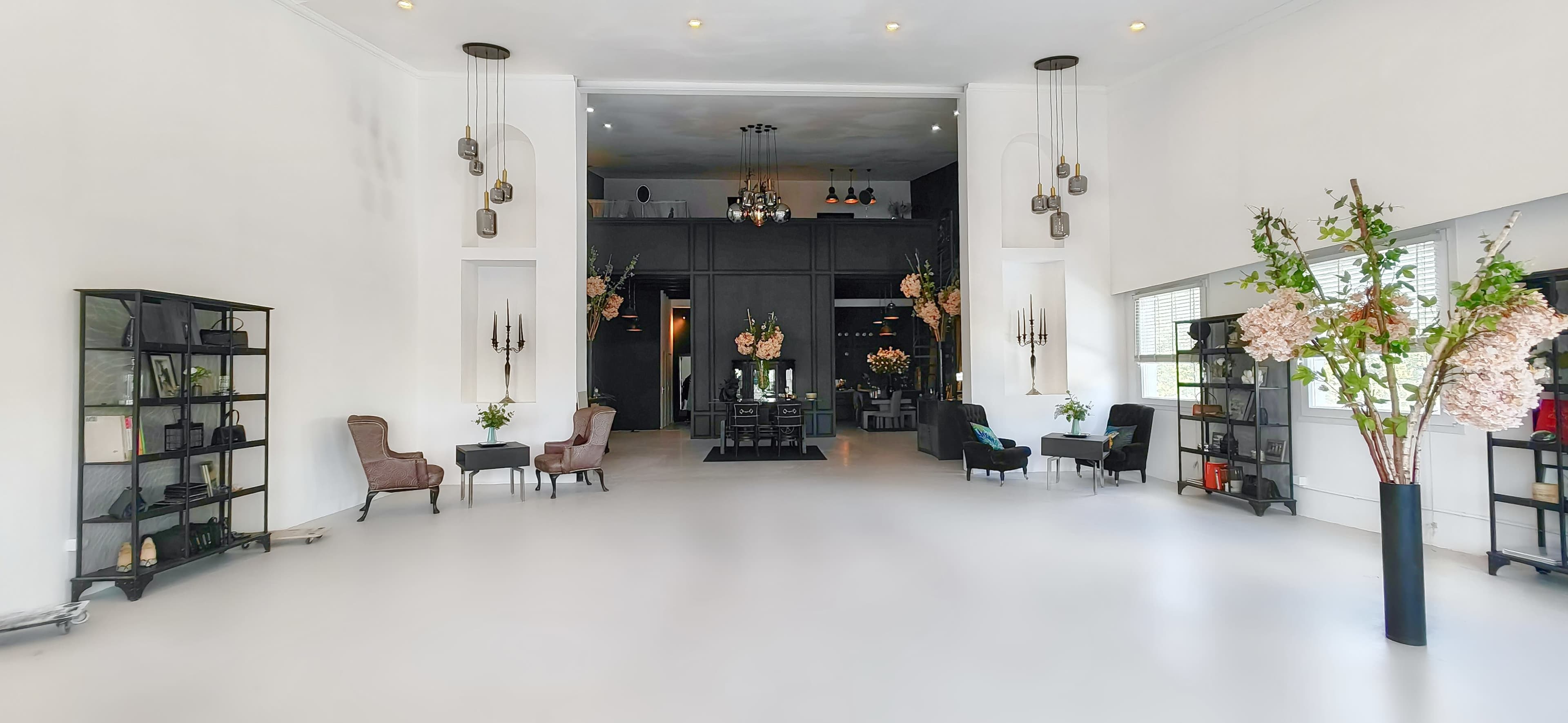 A spacious, well-lit interior featuring elegant furniture, floral arrangements, and decorative shelves in a modern setting.
