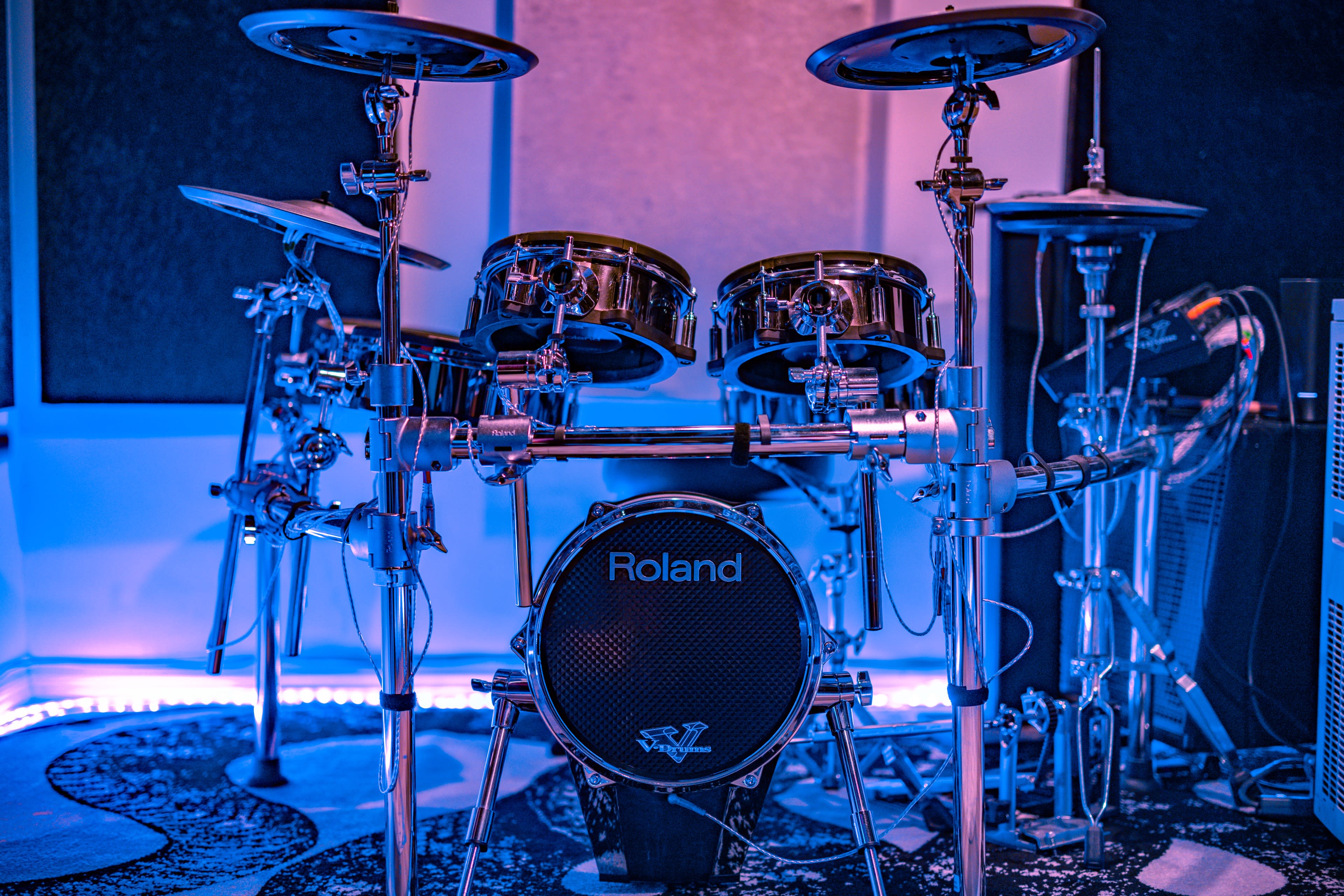 A Roland electronic drum set positioned in a room with blue lighting.