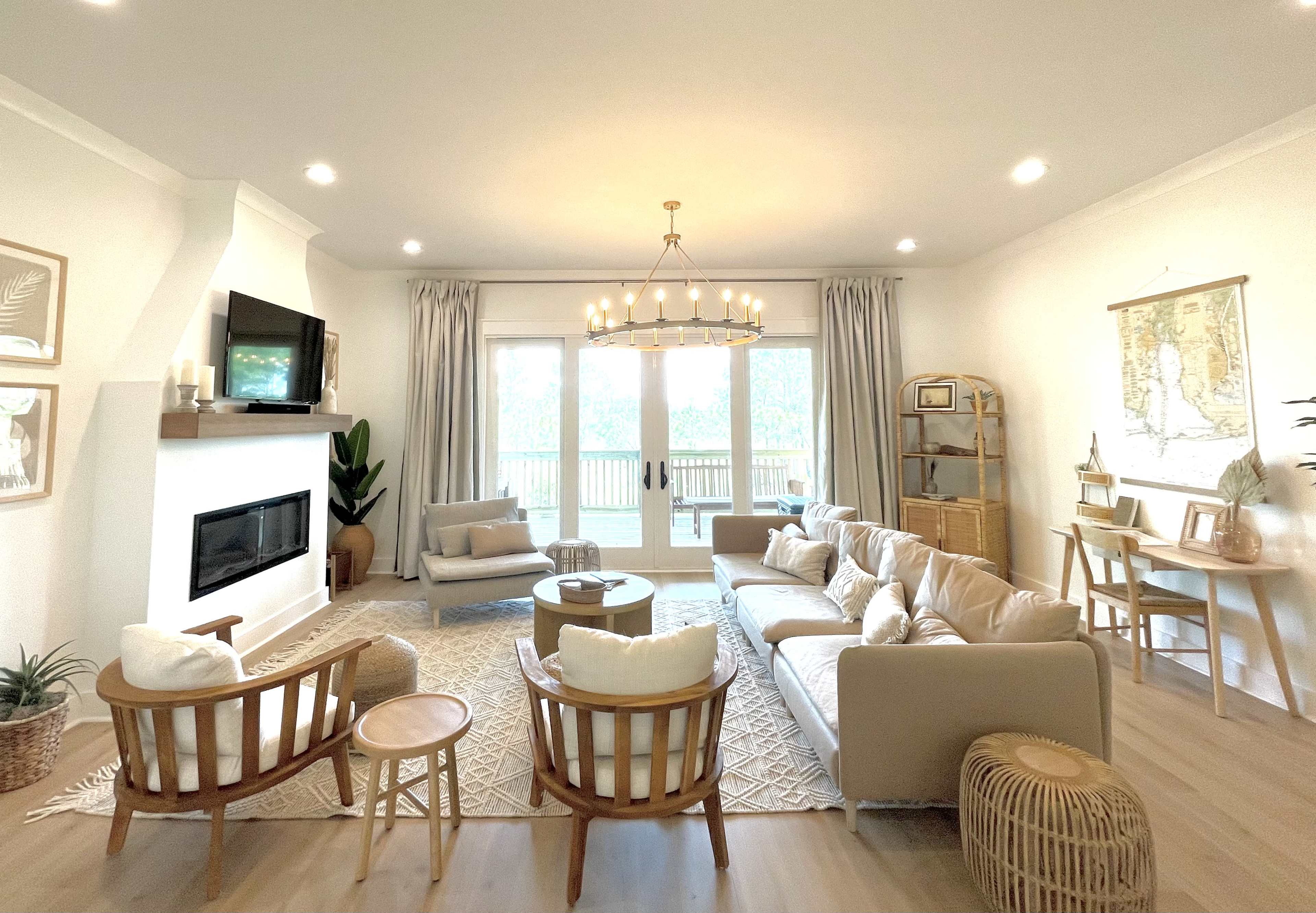 A bright, modern living room featuring a sectional sofa, two armchairs, a coffee table, and large windows with natural light streaming in.