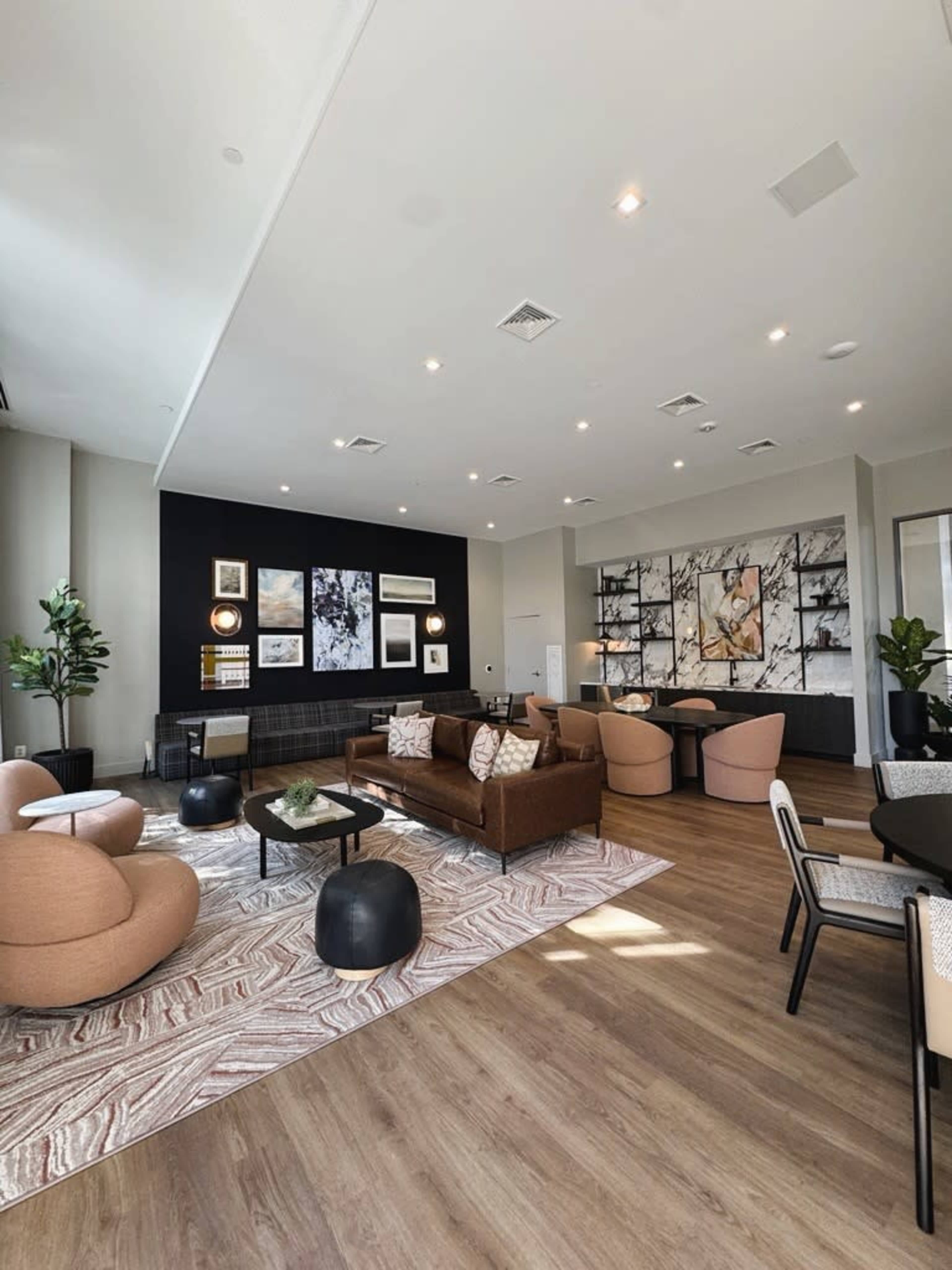 The image shows a modern lounge area with upholstered furniture, decorative artwork on the walls, and hardwood flooring.