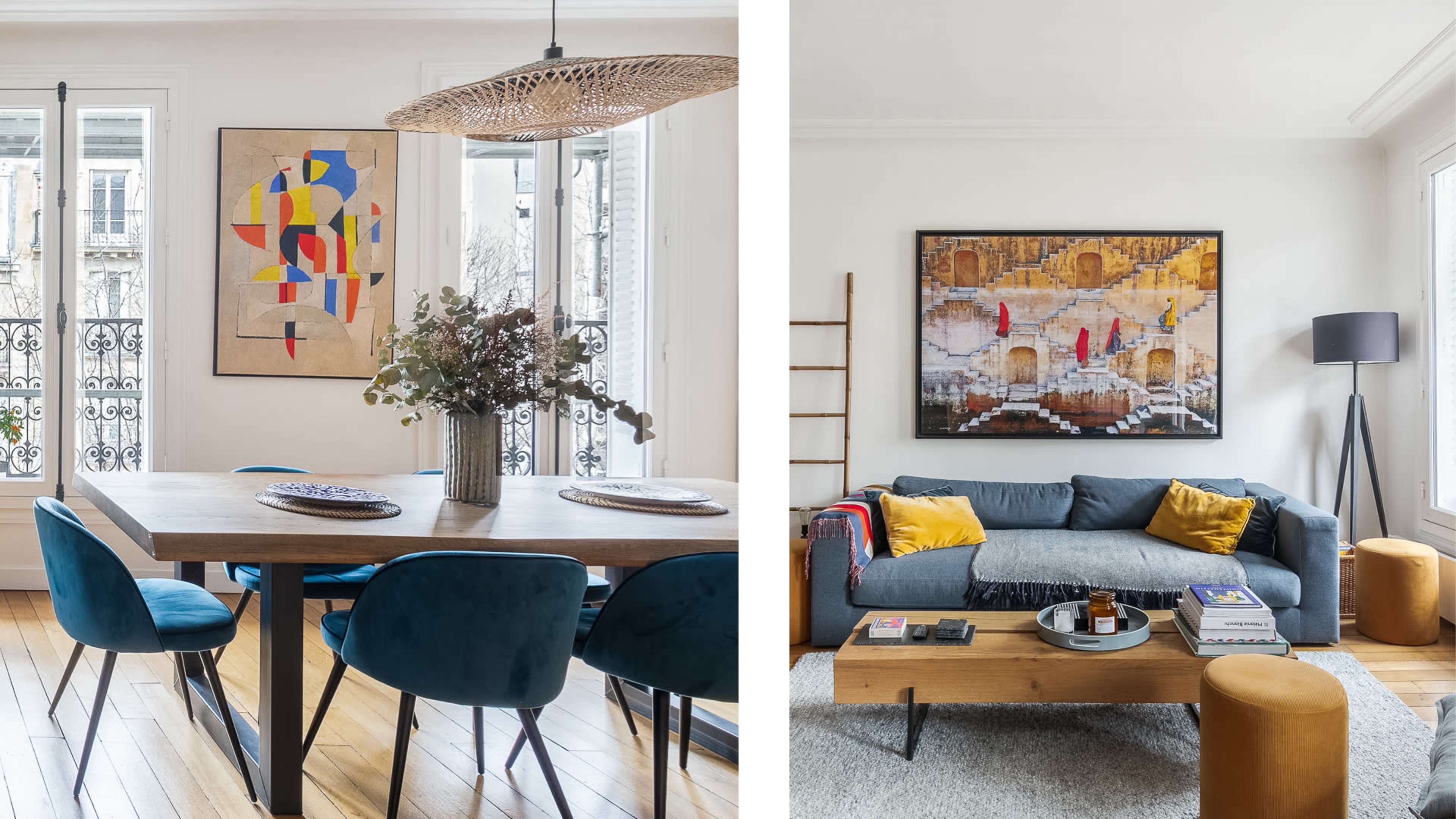 A dining area with a wooden table and blue chairs on the left, and a living room featuring a gray sofa, a wooden coffee table, and artwork on the right.