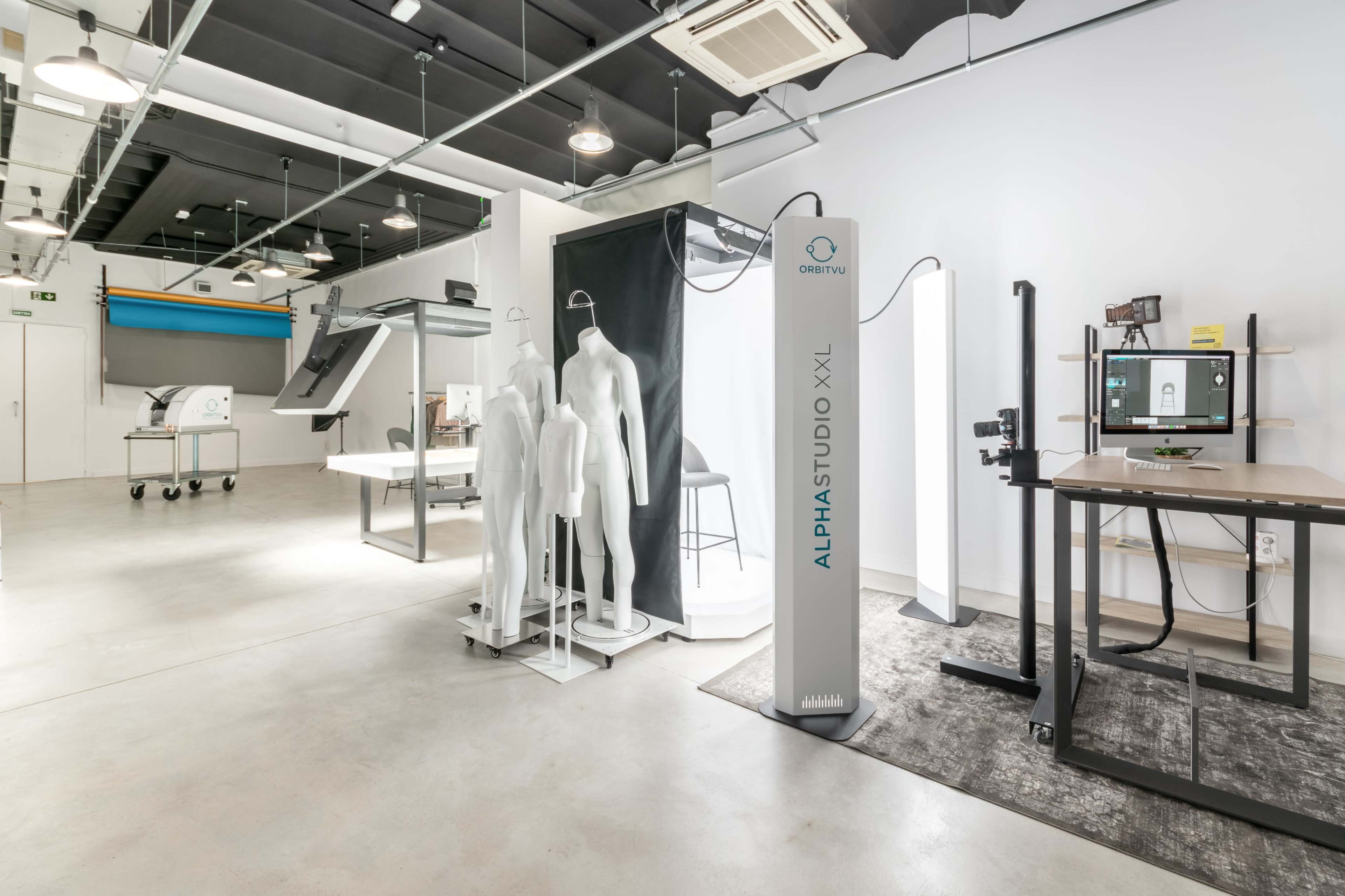 A modern studio space featuring a variety of equipment, including mannequins, a digital display, and a large standing panel labeled "ALPHASTUDIO XXL."