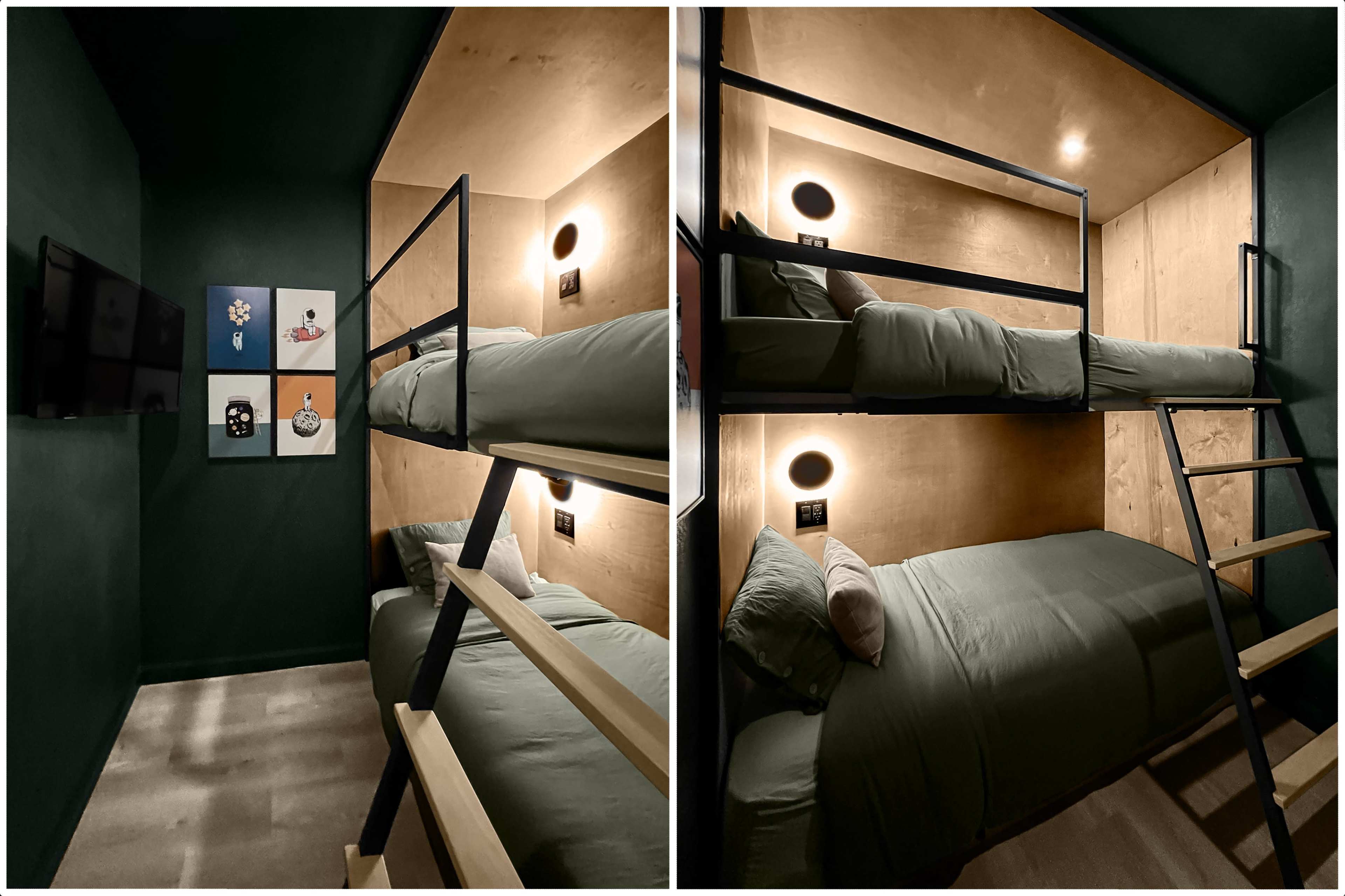 The image shows a small, modern bedroom with two sets of bunk beds and minimalist wooden walls, featuring a television and framed artwork on the wall.