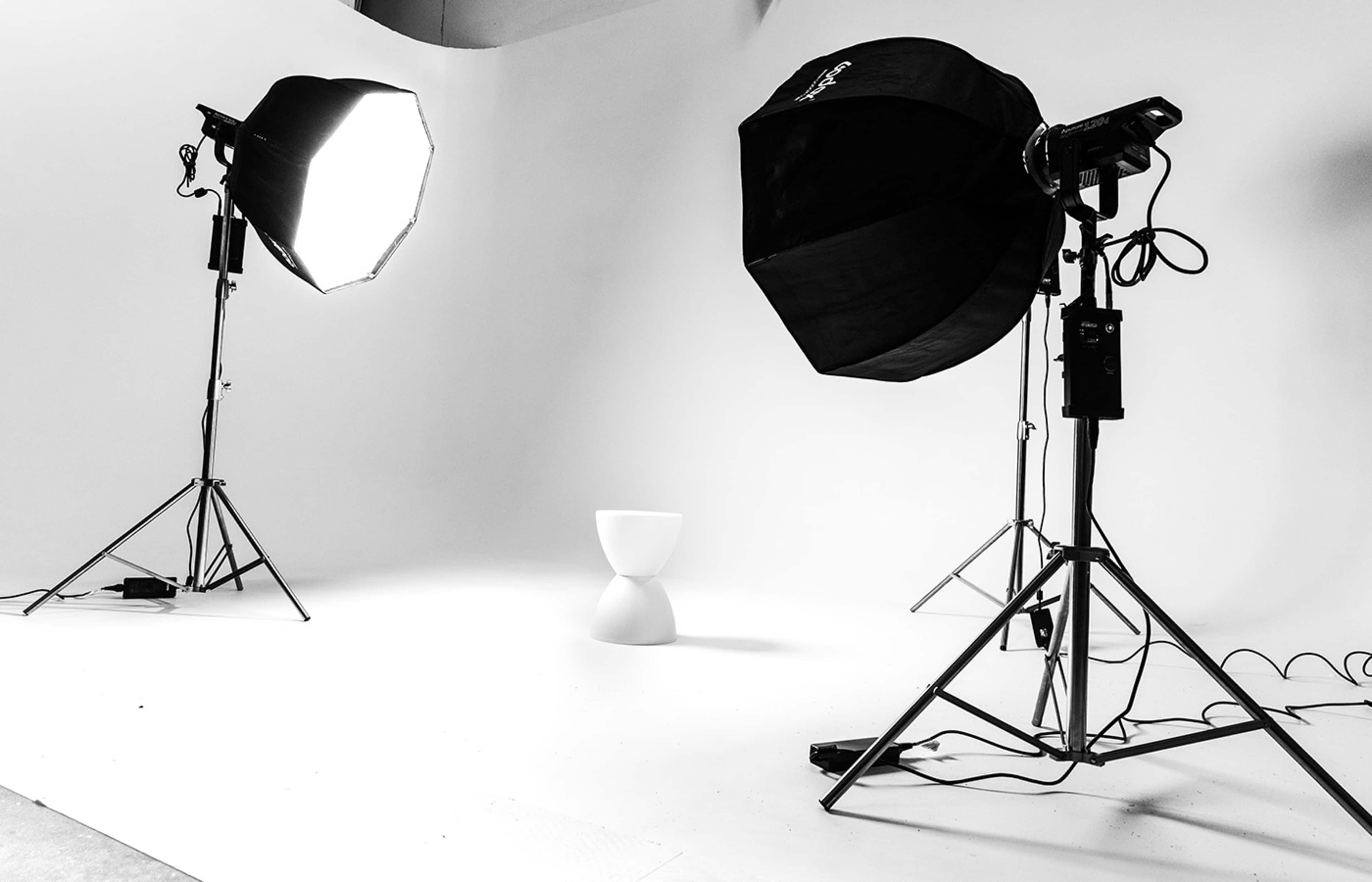 A photography studio with two light sources positioned on either side of a minimalist white pedestal.