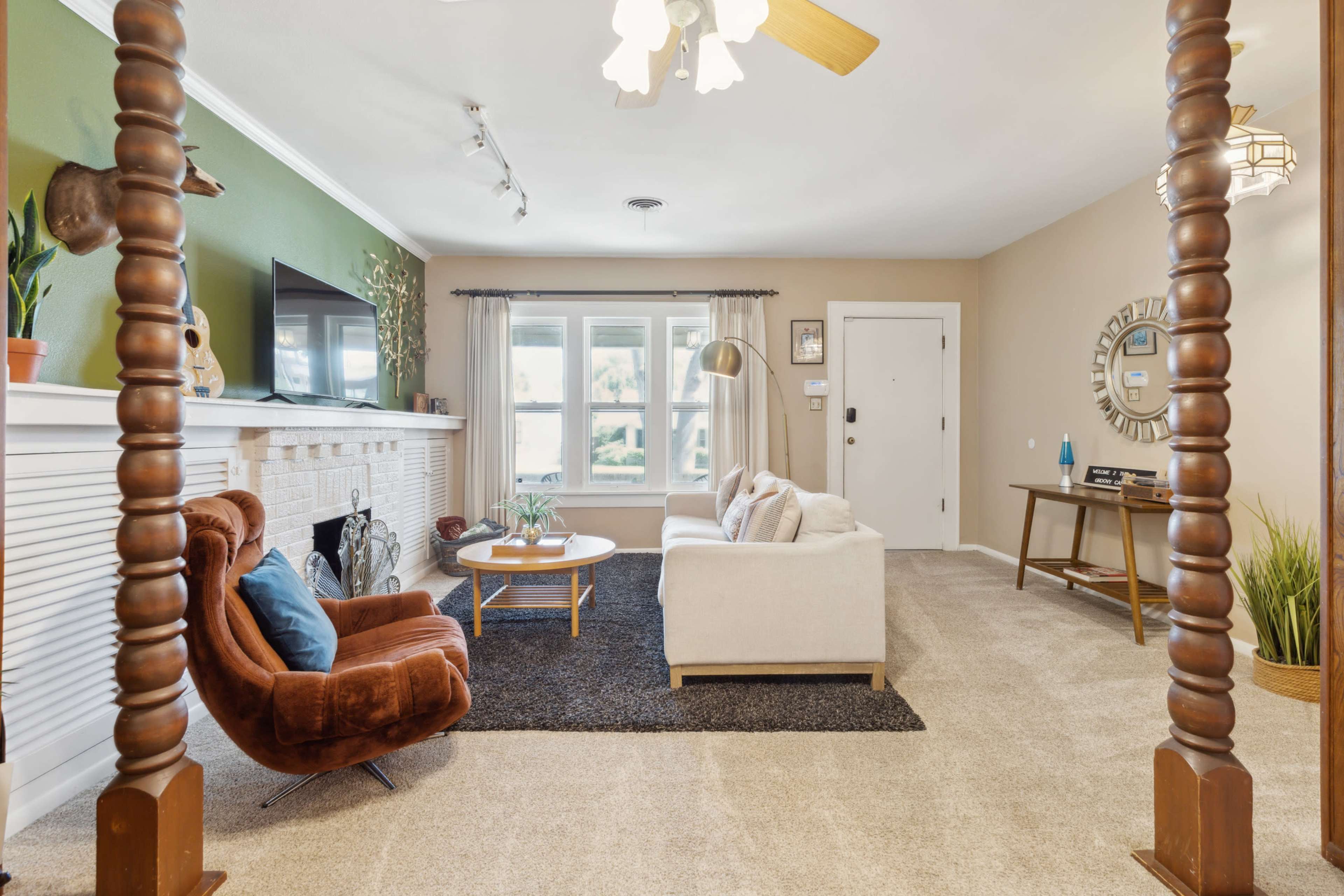 The living room features a comfortable seating area with a sofa and a brown armchair, a fireplace, and large windows that allow natural light to enter.