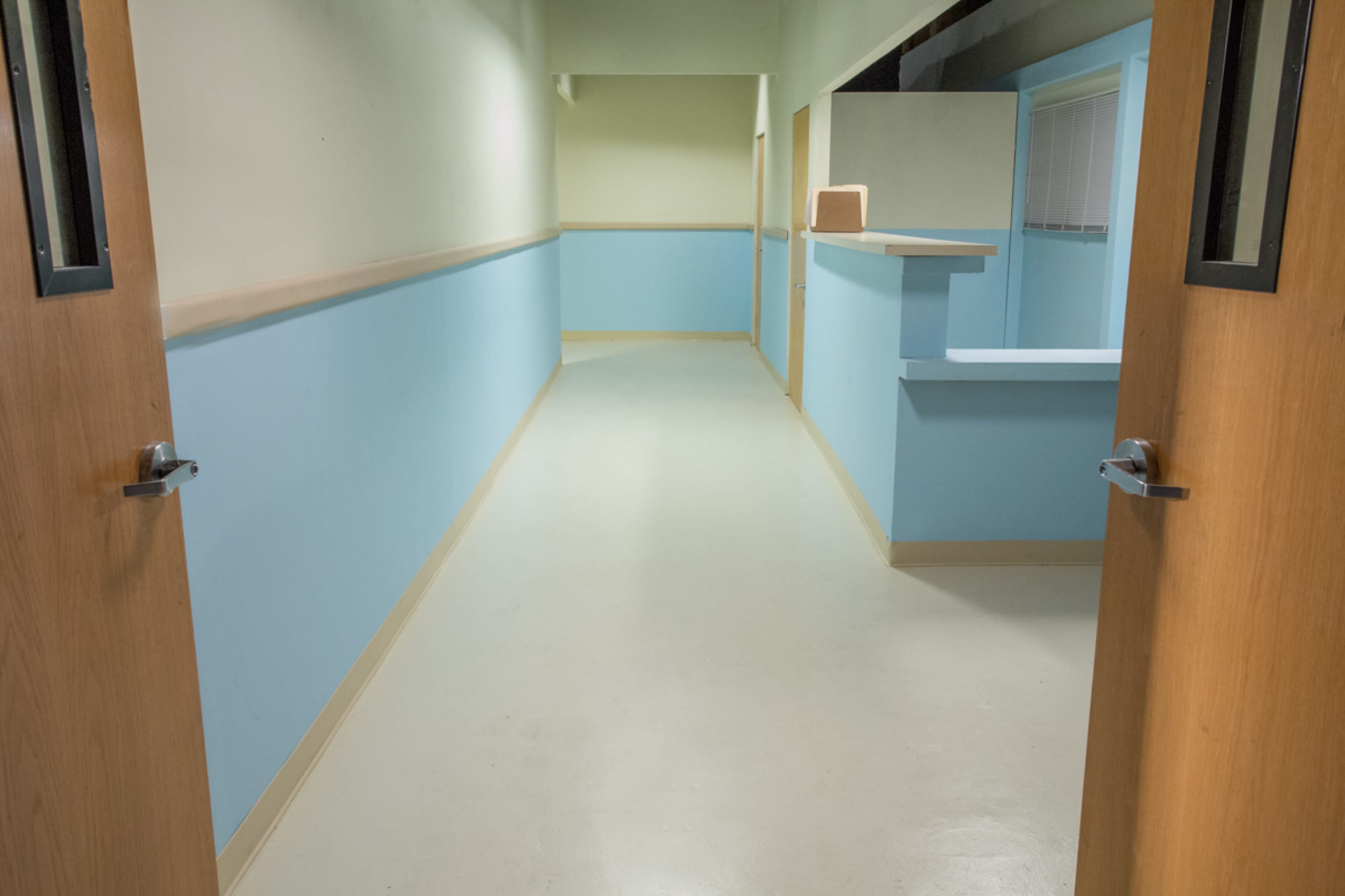 A long hallway with light blue walls and two doors open on either side, leading to separate rooms.