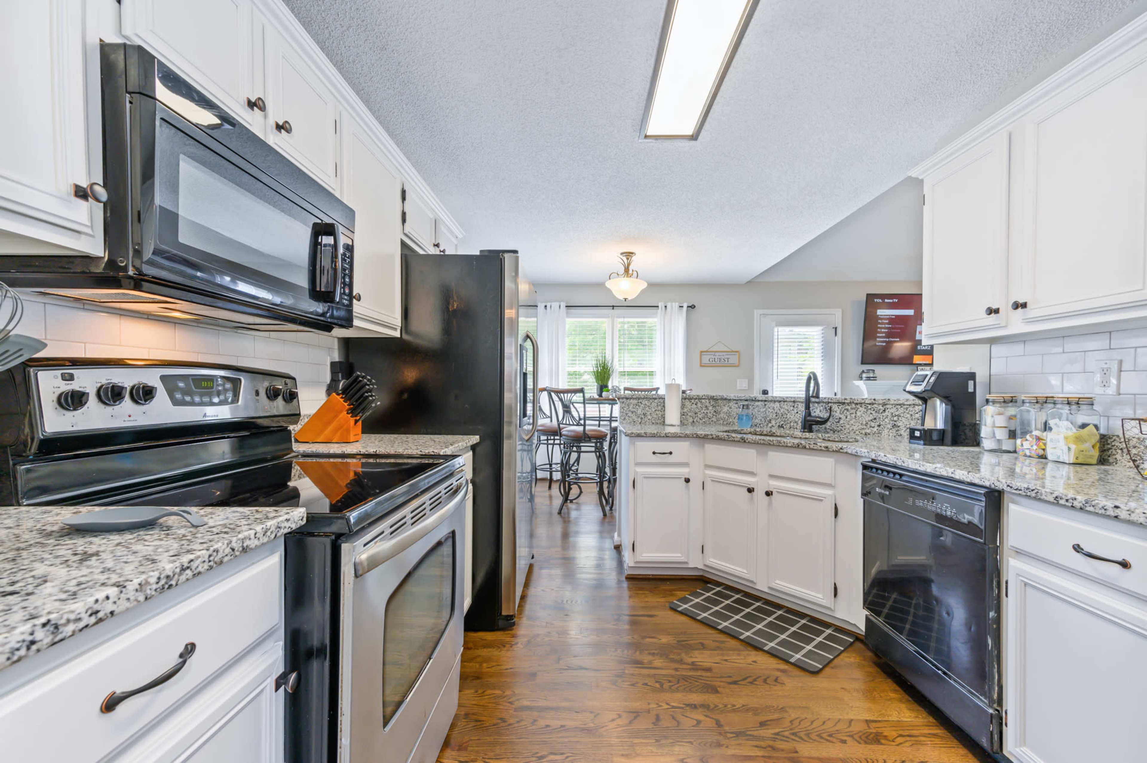 A kitchen features white cabinets, stainless steel appliances, granite countertops, and hardwood floors.