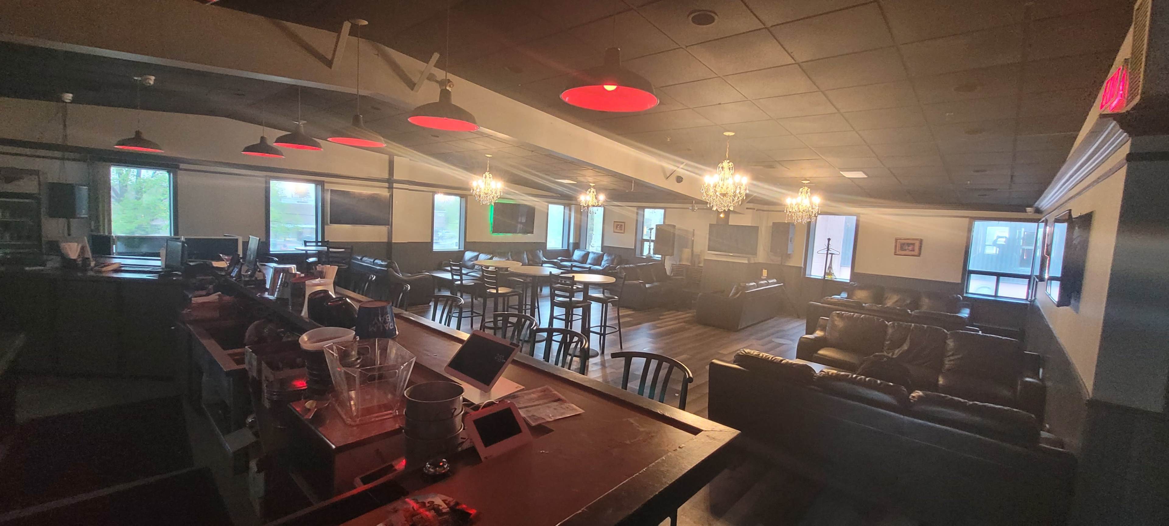 A dimly lit cafe or lounge with leather seating, tabletop games, and a bar area.