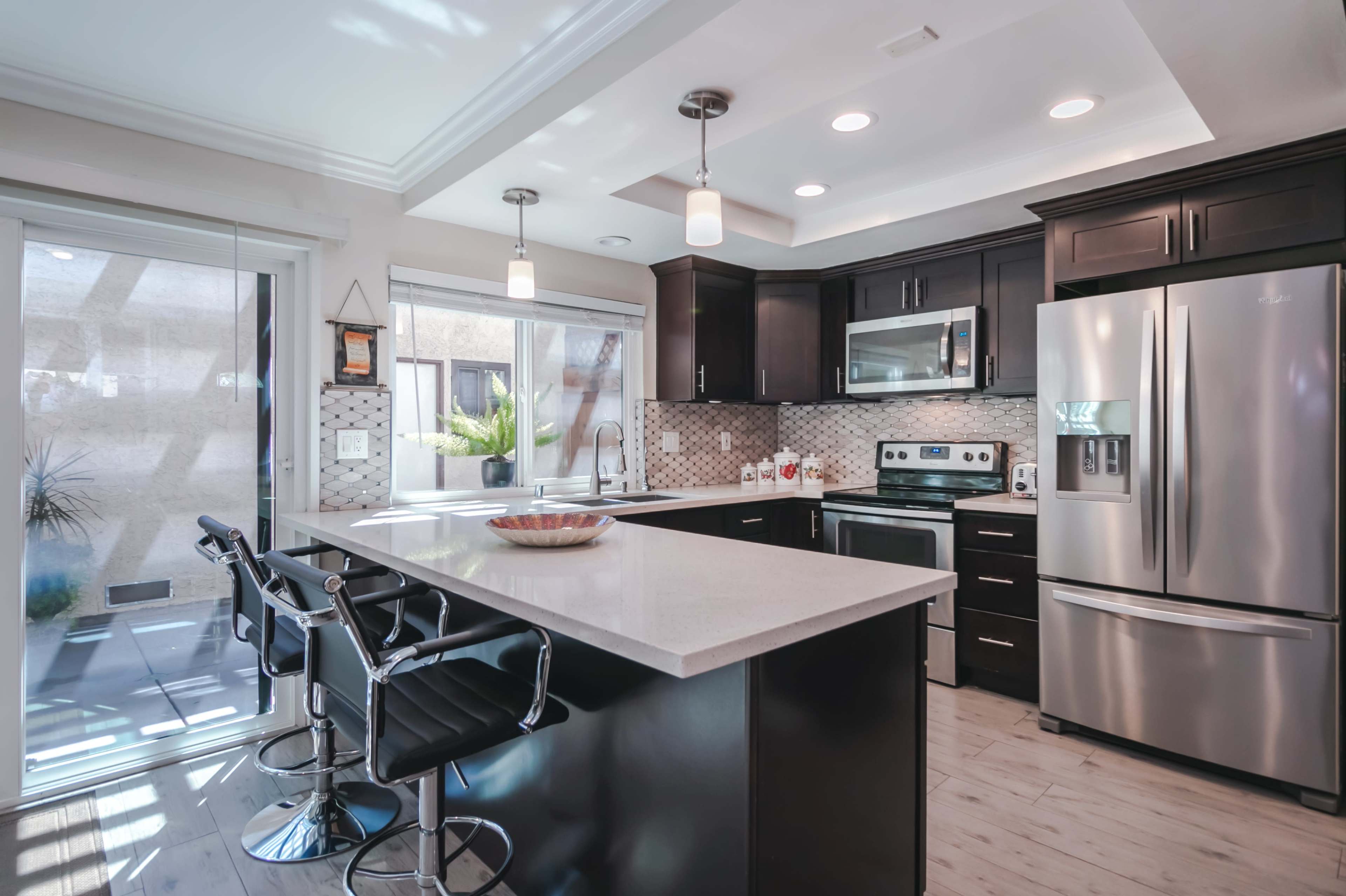 A modern kitchen features dark cabinetry, stainless steel appliances, and a central island with bar seating.
