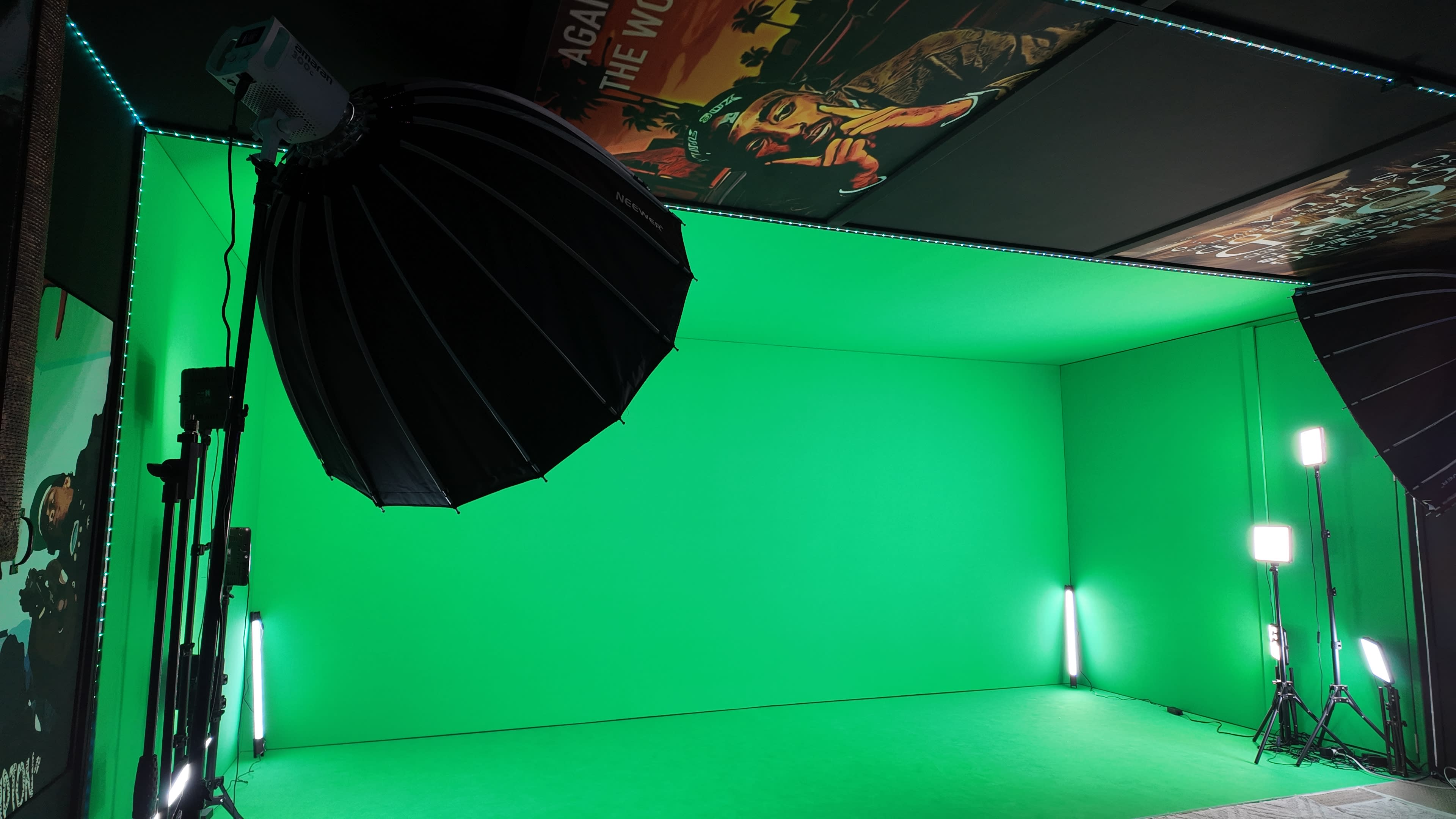 The image depicts a studio setup with a green backdrop, softbox lighting, and posters on the ceiling.