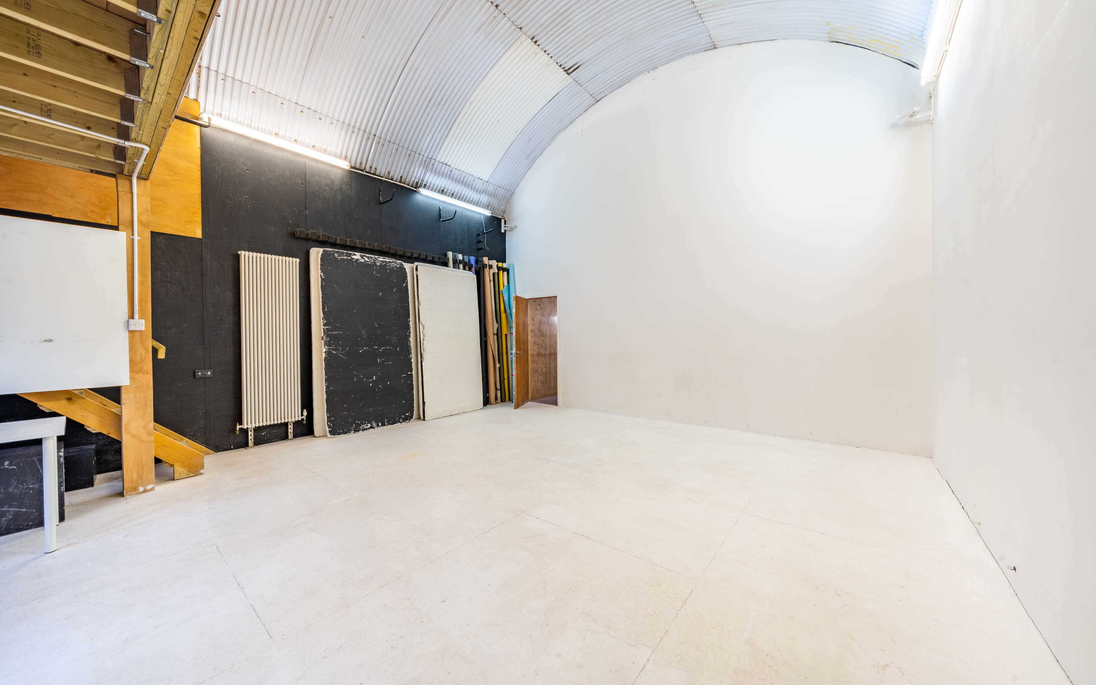 An empty studio space with a curved ceiling, white walls, and light flooring.