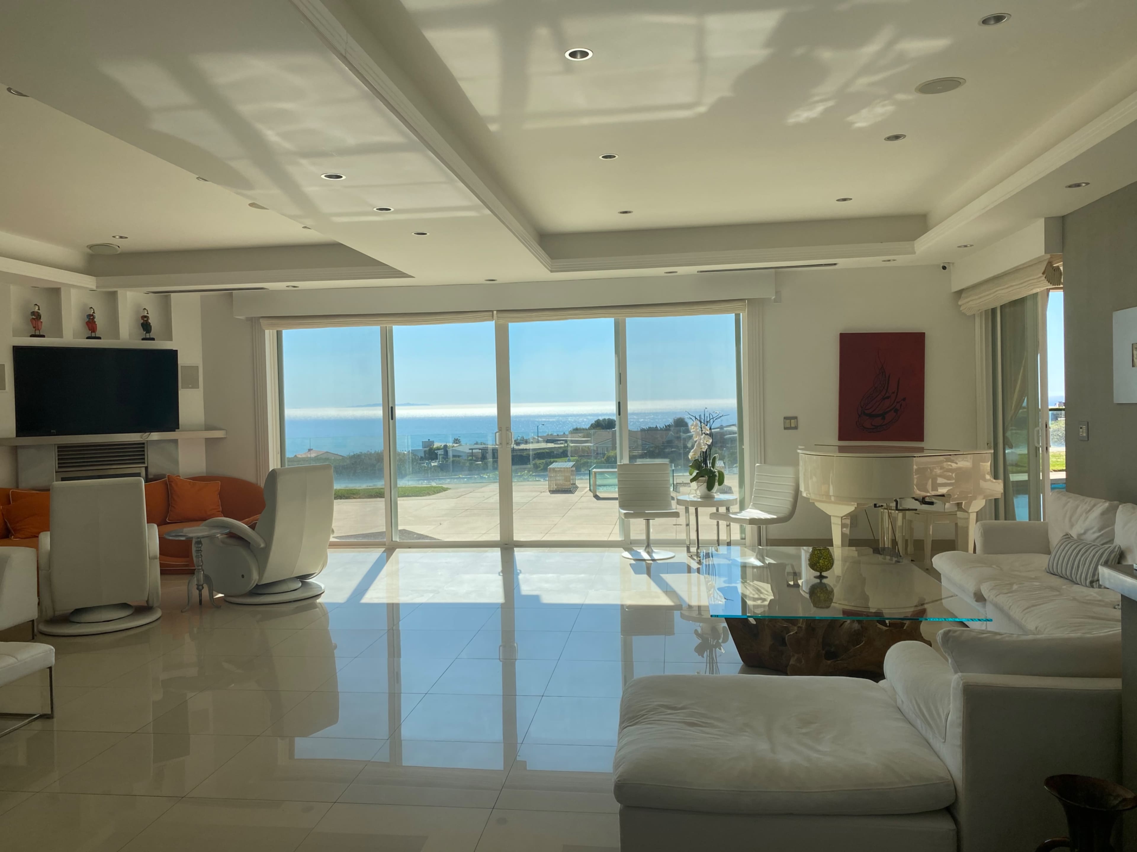 A spacious living room features modern furniture and large windows overlooking a coastal view.