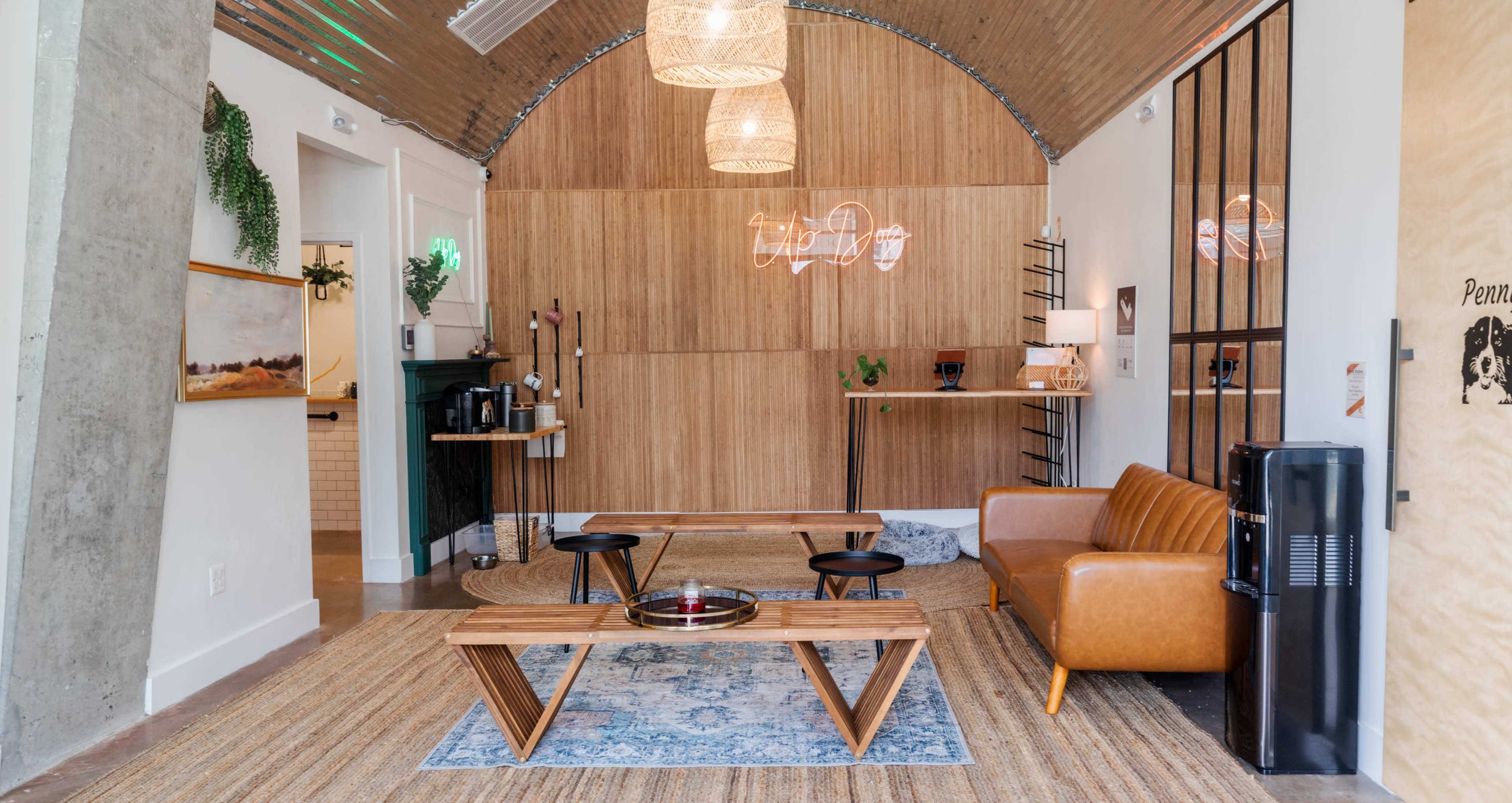 A modern lounge area featuring wooden paneling, a brown leather sofa, a geometric coffee table, and decorative lighting.