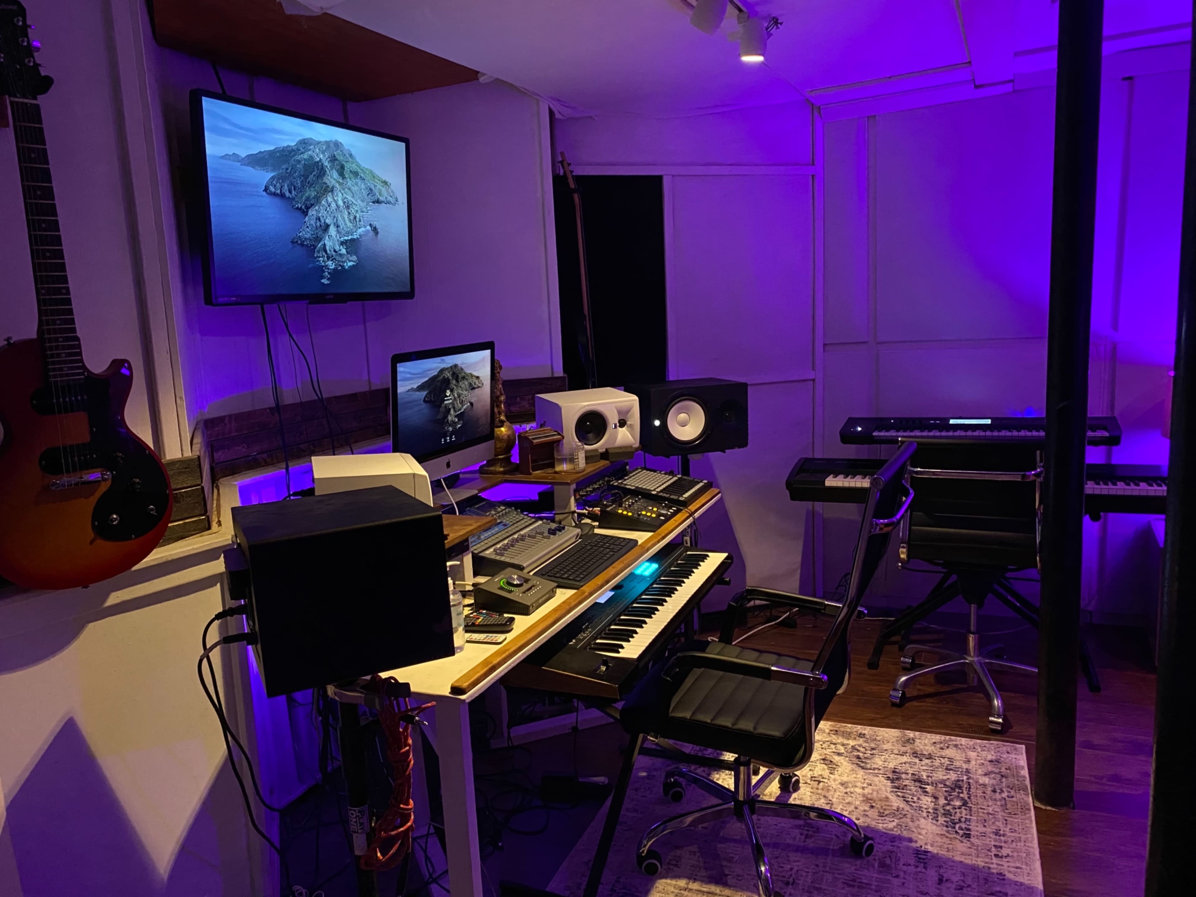 The image features a music production studio with a keyboard, audio equipment, and multiple screens, illuminated by purple lighting.