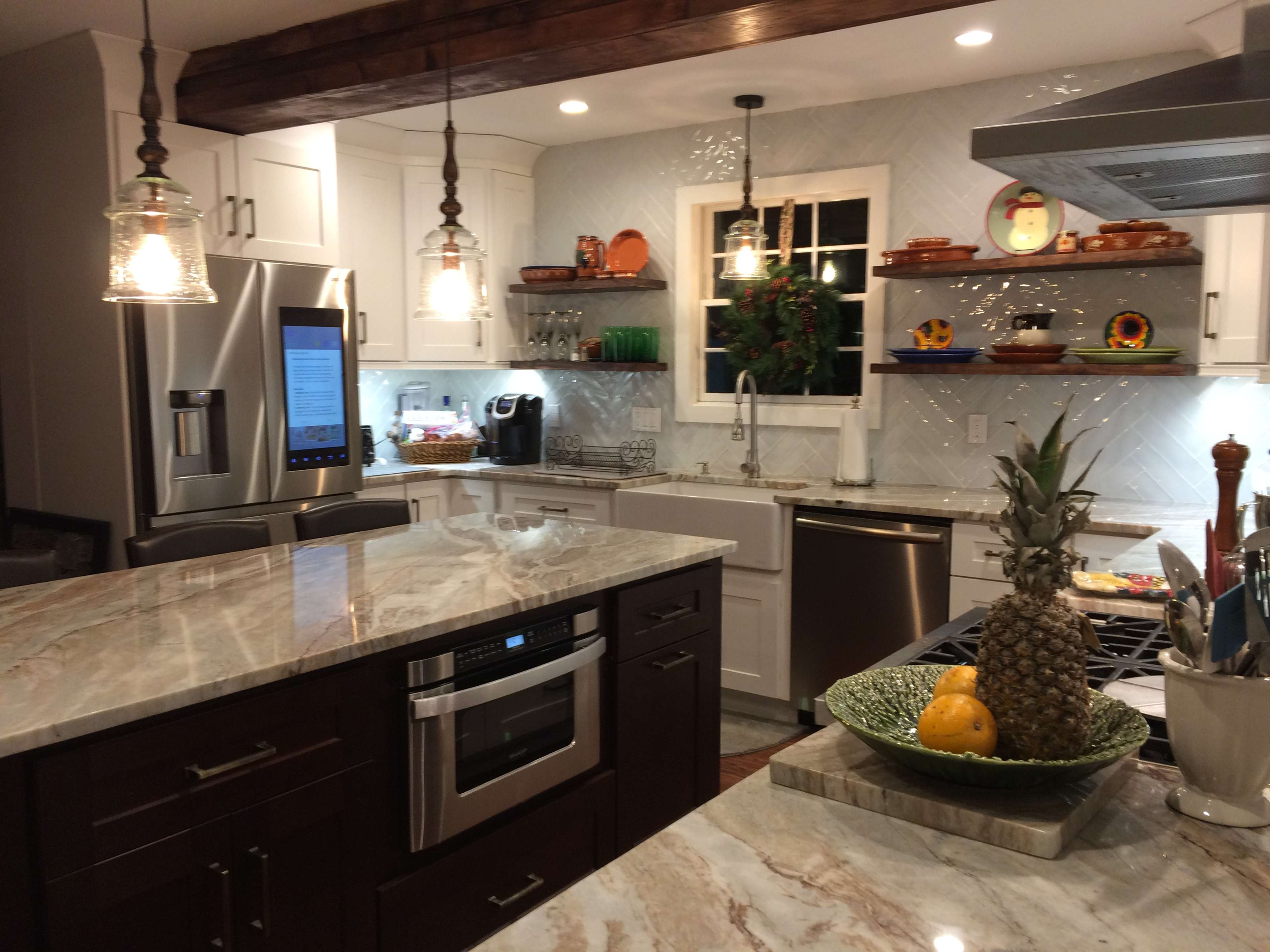 A modern kitchen features a large island with a marble countertop, stainless steel appliances, and decorative shelves.