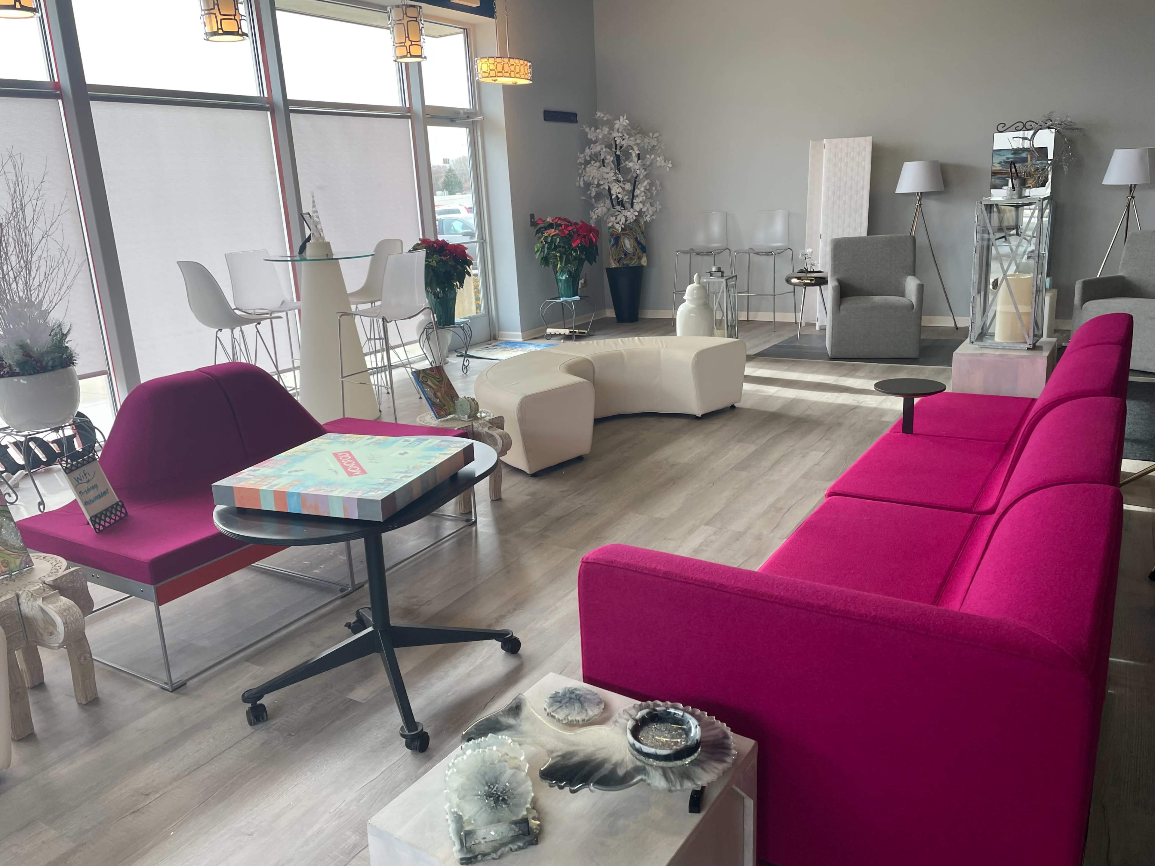 A modern interior space featuring a pink sofa, an array of furniture pieces, and decor items in a well-lit environment.