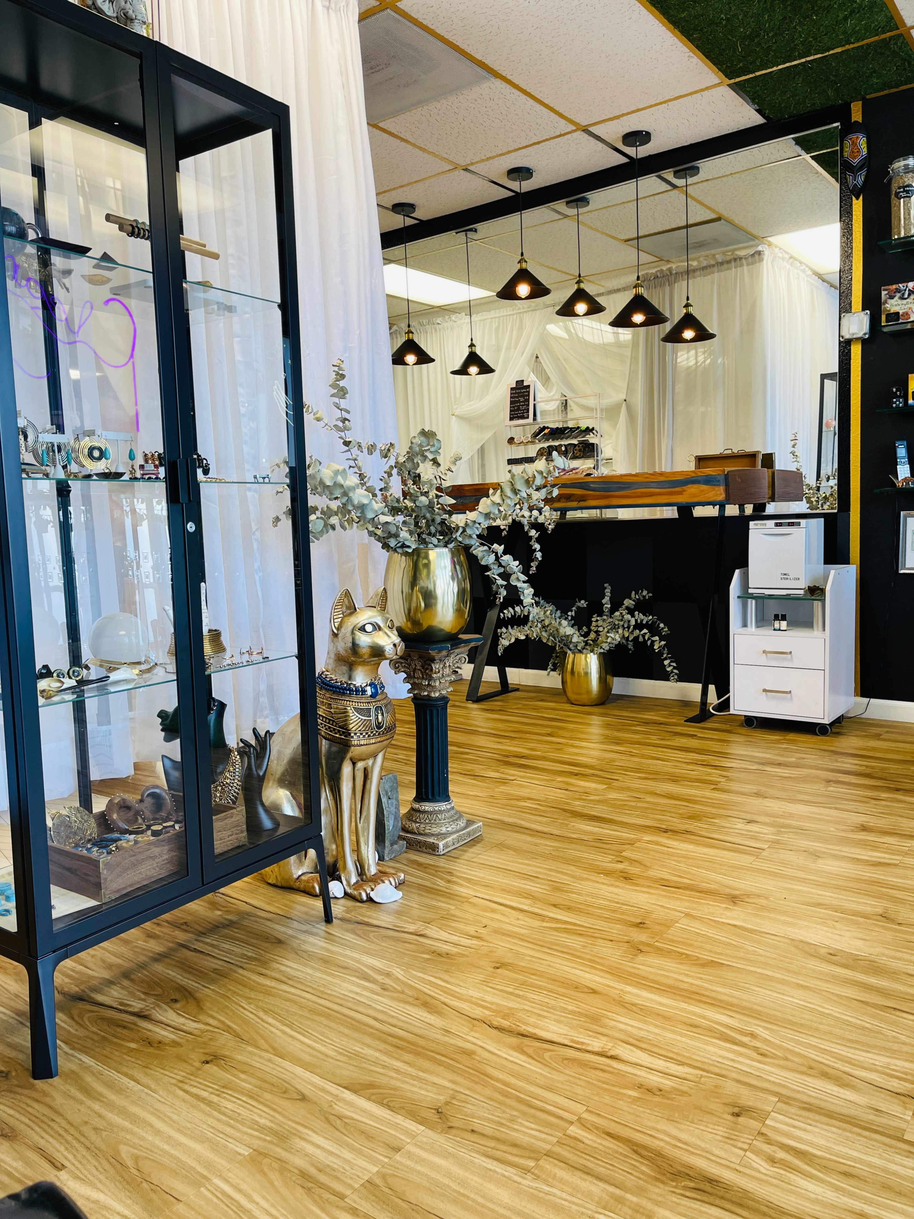 The image depicts a modern interior space featuring a display cabinet, a decorative dog statue, and a wooden counter under pendant lighting.