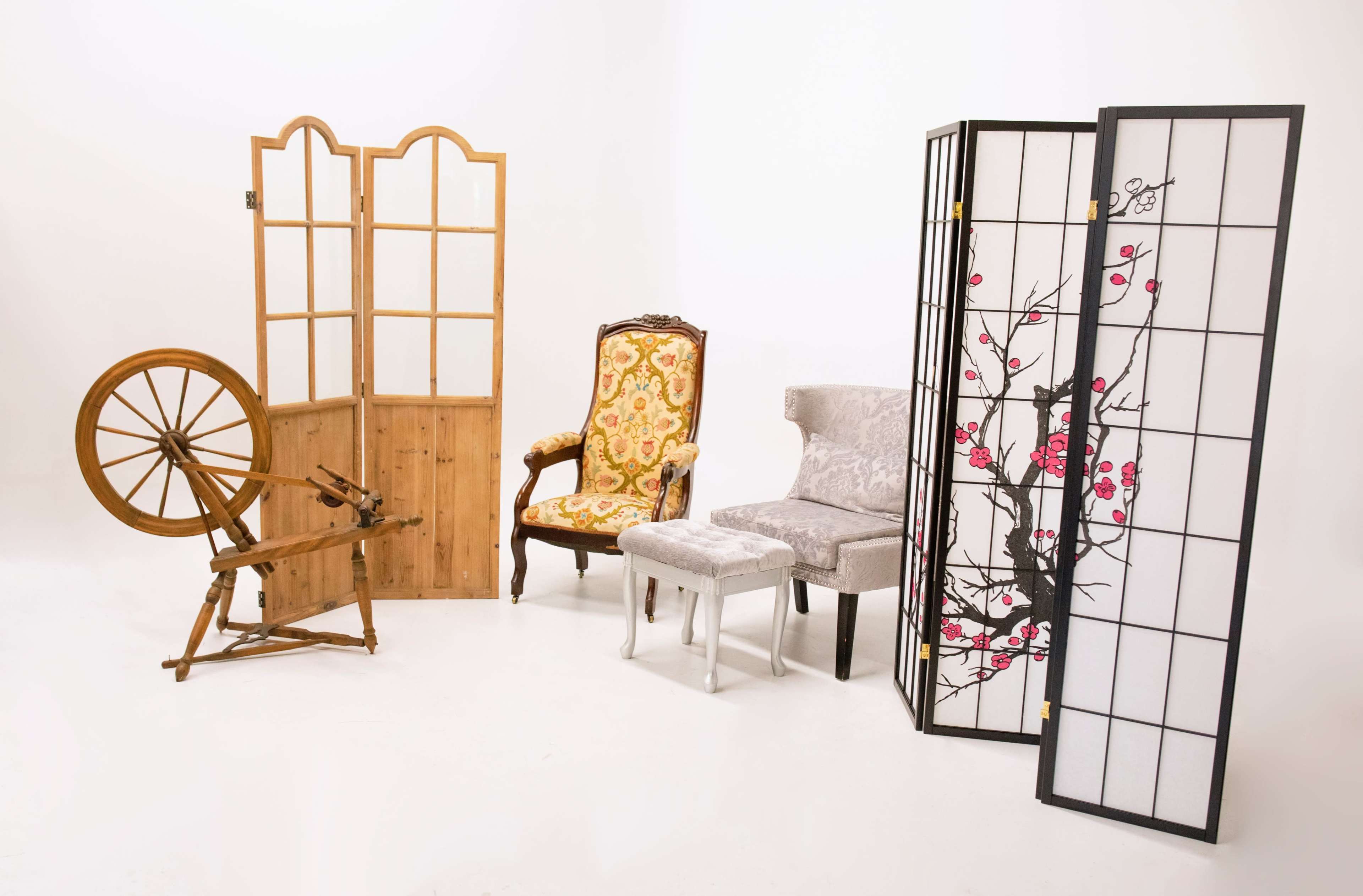 The image features a wooden spinning wheel and three chairs, with two decorative folding screens positioned around them.