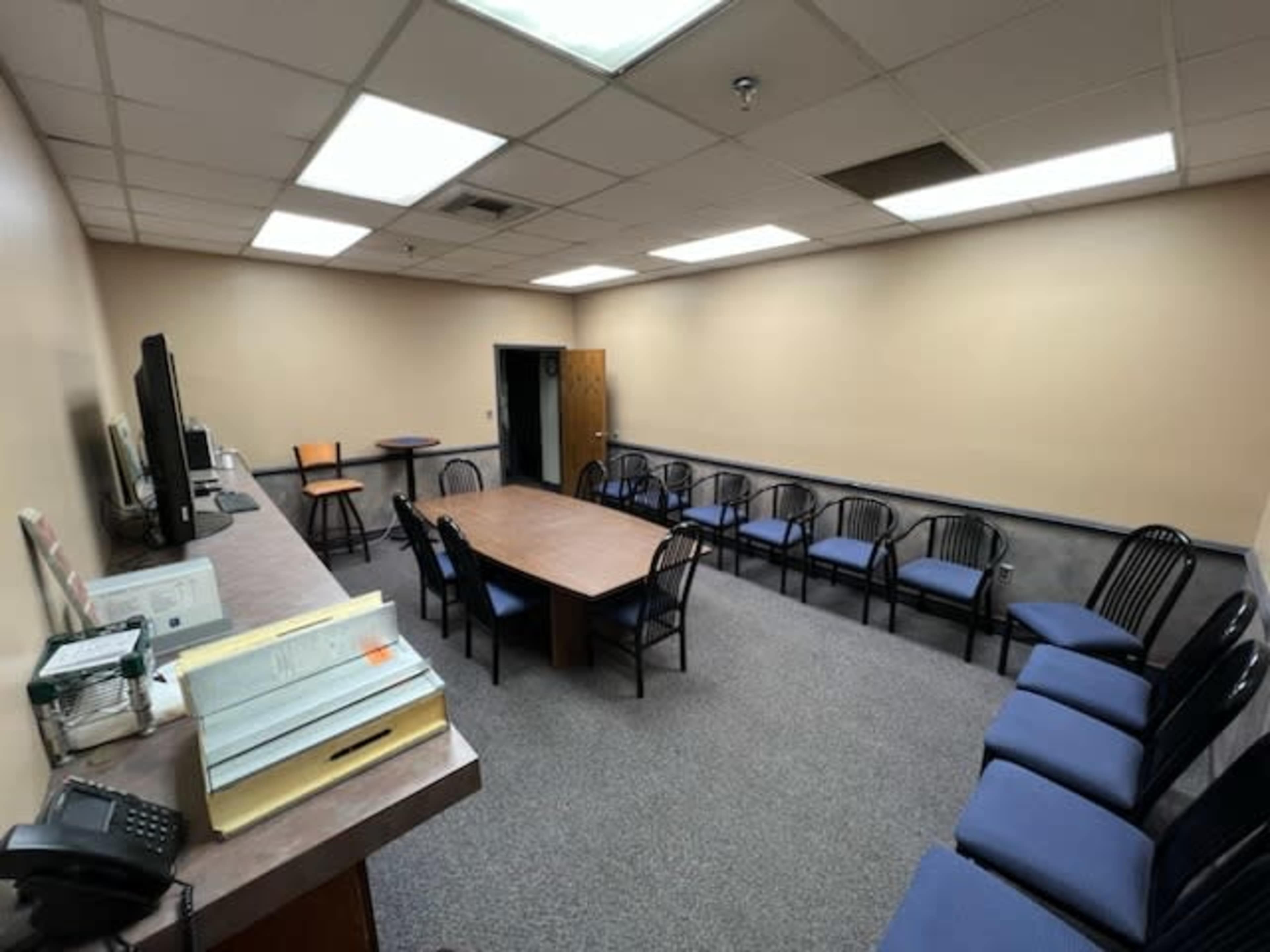A meeting room with a central table surrounded by chairs and a television mounted on the wall.
