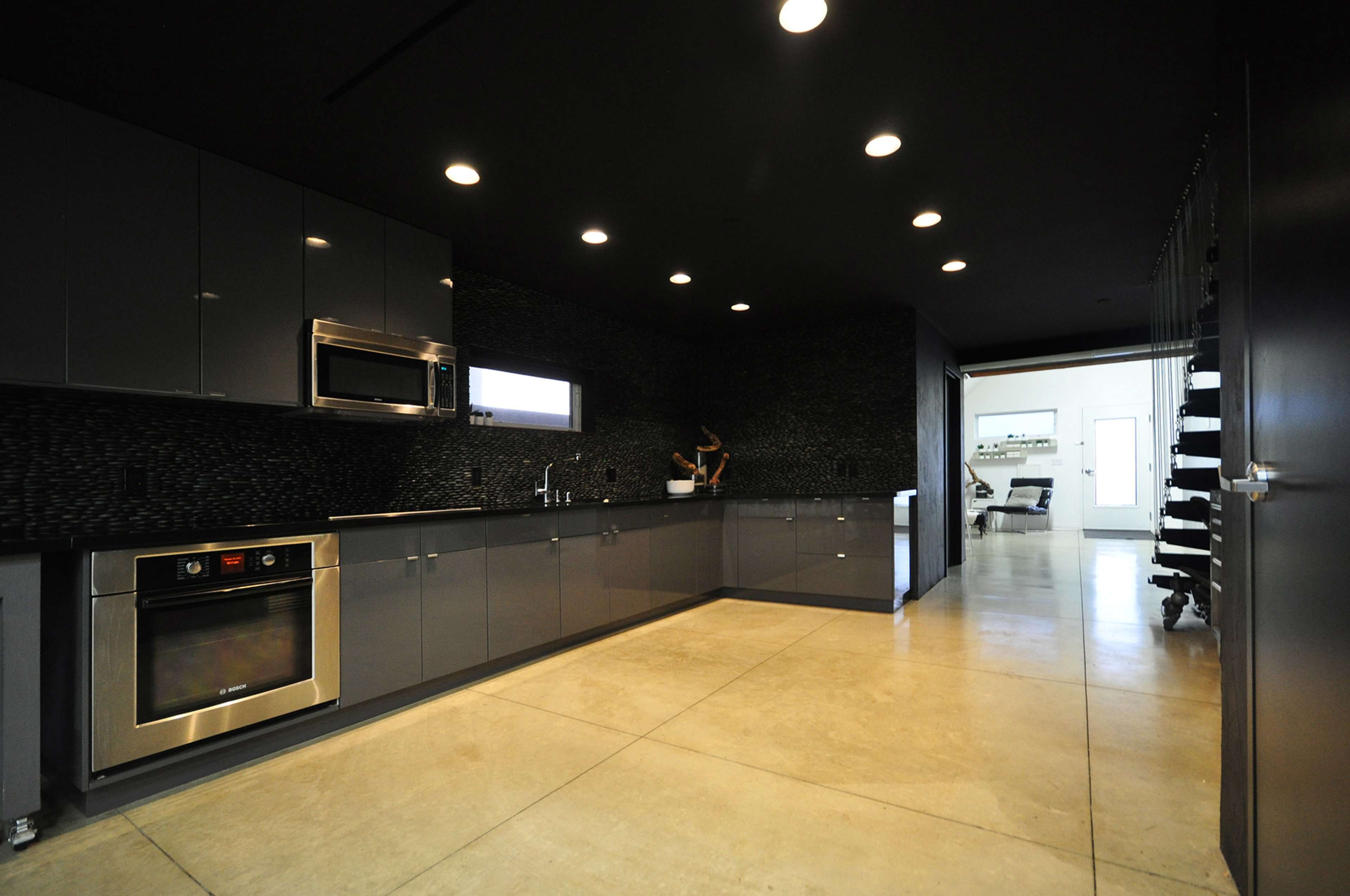 A modern kitchen features sleek gray cabinetry, minimalist design, and a large counter space with stainless steel appliances.