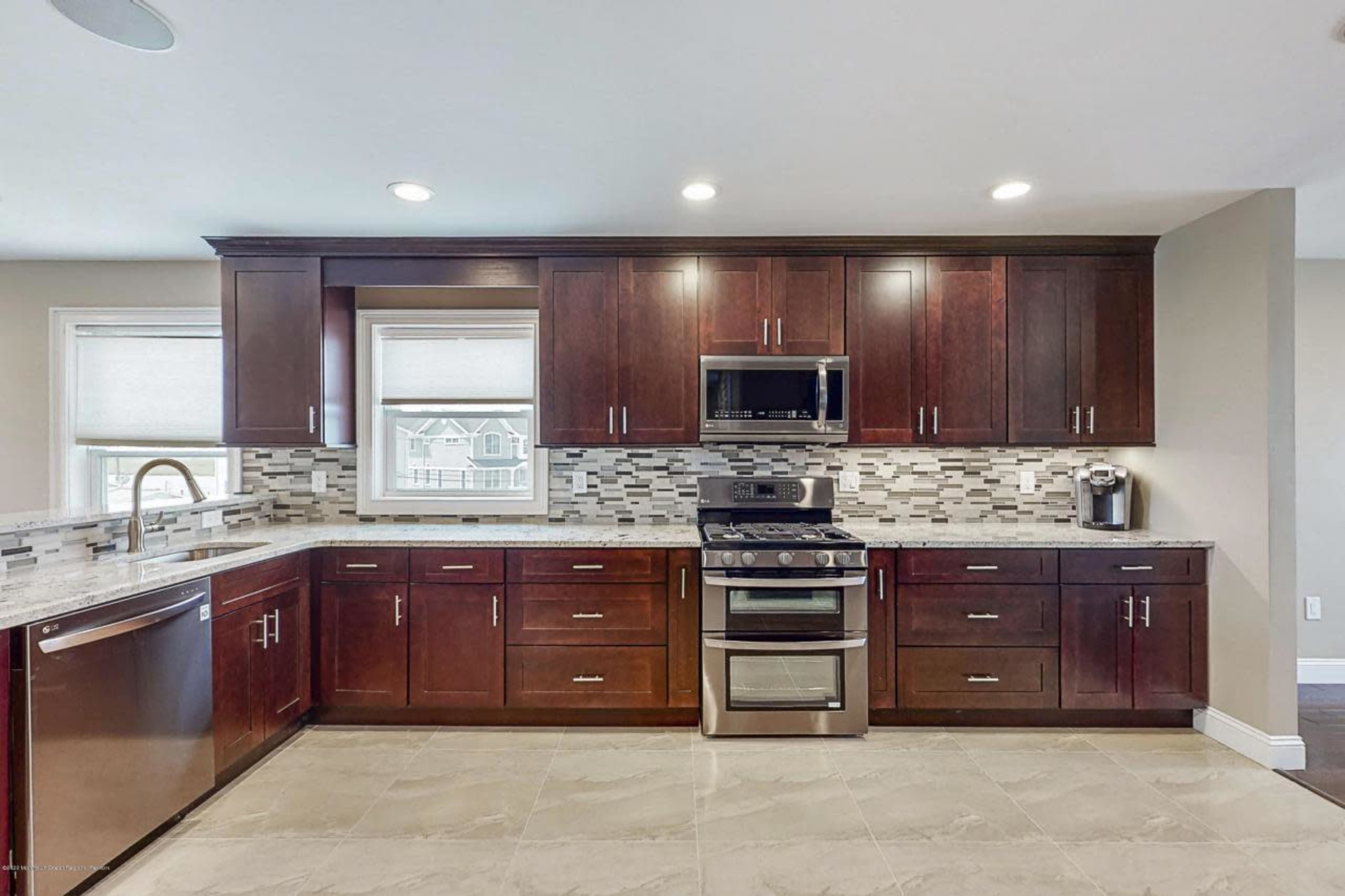A modern kitchen with dark wood cabinets, stainless steel appliances, and a tiled backsplash.
