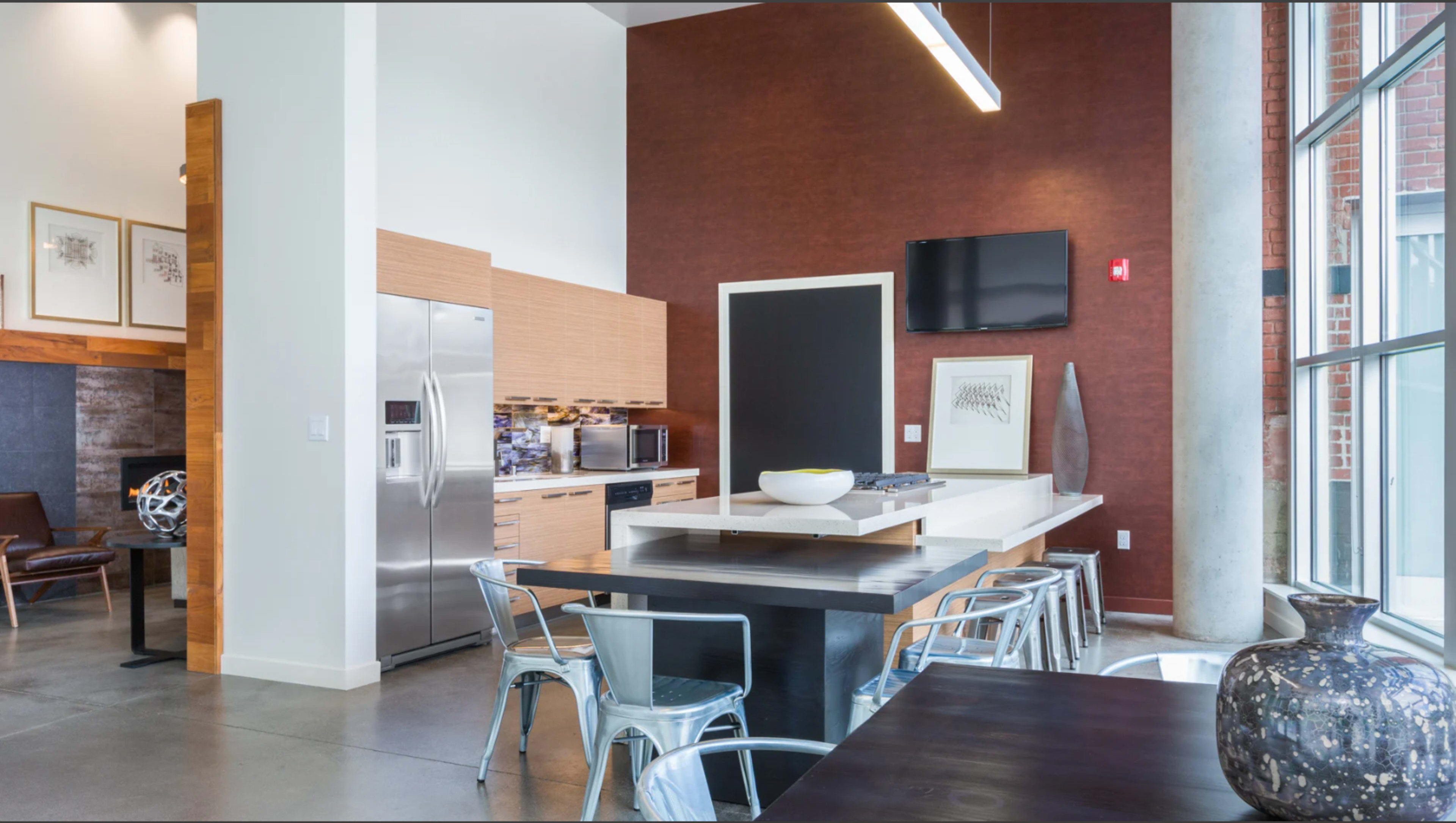 A modern kitchen and dining area with stainless steel appliances, a large kitchen island, and a mix of wooden and metal furnishings.