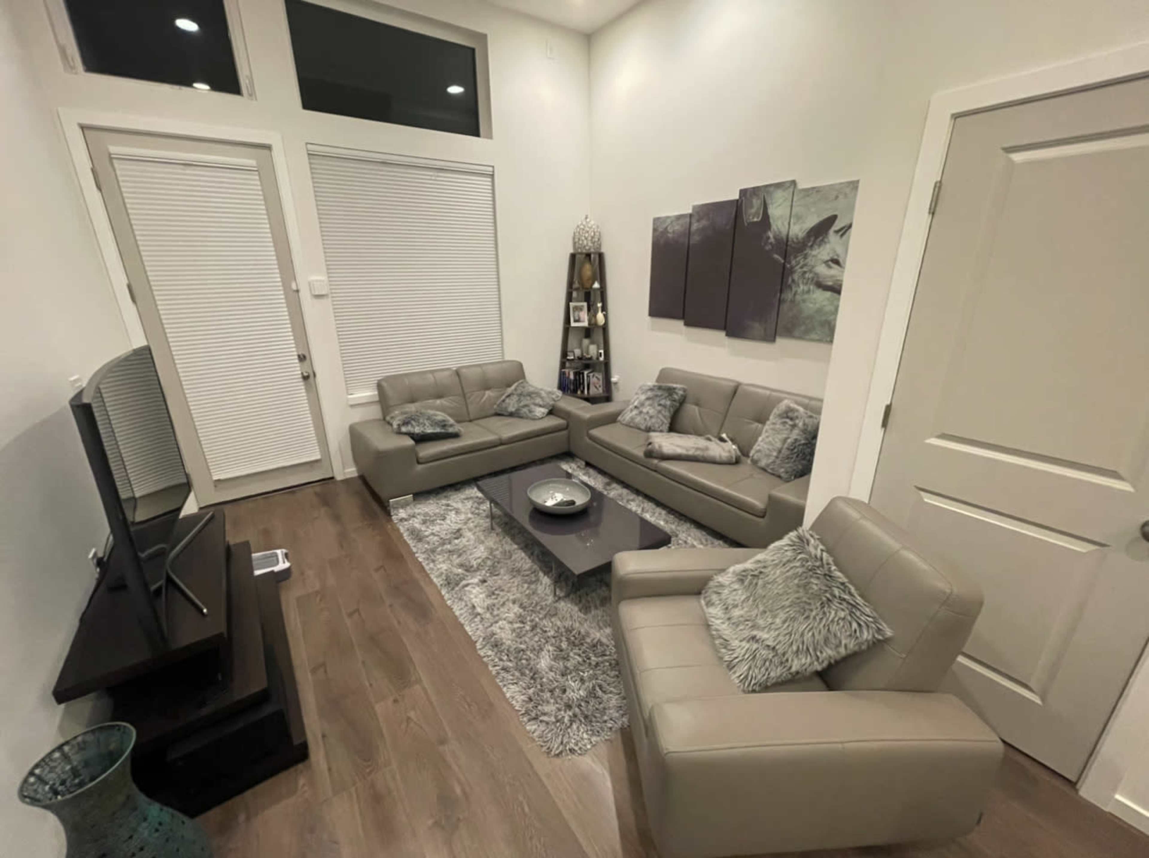 A modern living room furnished with gray couches, a coffee table, and a television against a light-colored wall.