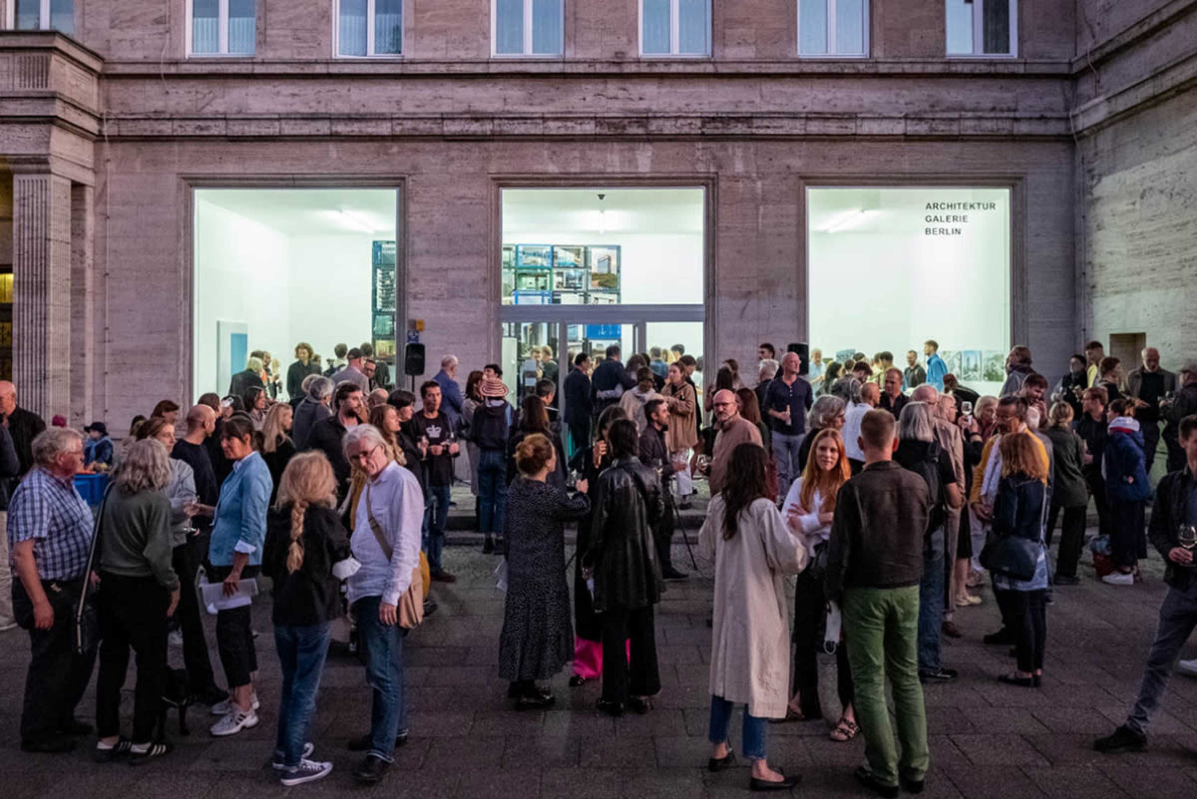 A large crowd gathers outside the Architecture Gallery in Berlin during an evening event.
