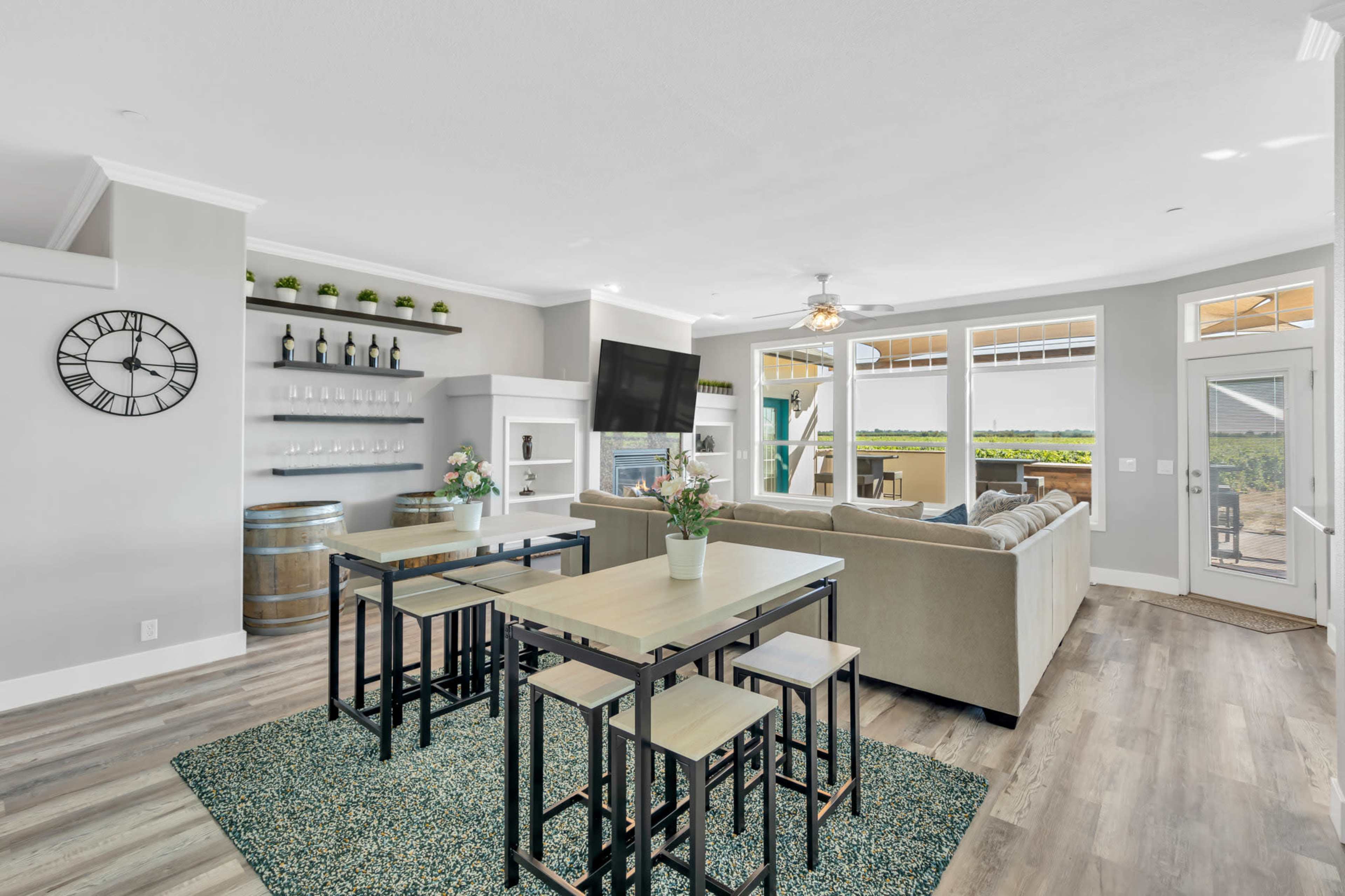 A modern living area with a seating arrangement, dining table, and large windows offering a view of the outdoors.