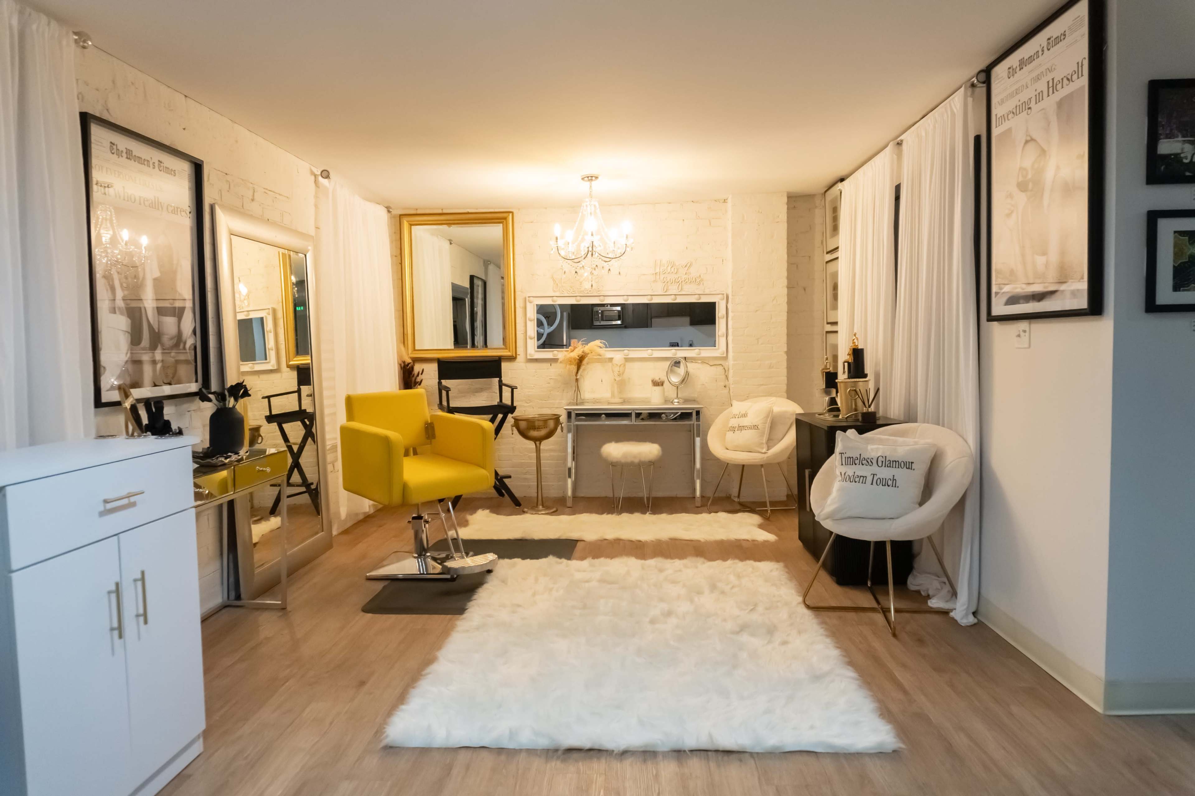 The image shows a stylish salon interior featuring a yellow salon chair, large mirrors, a vanity area, and a plush white rug on a wooden floor.
