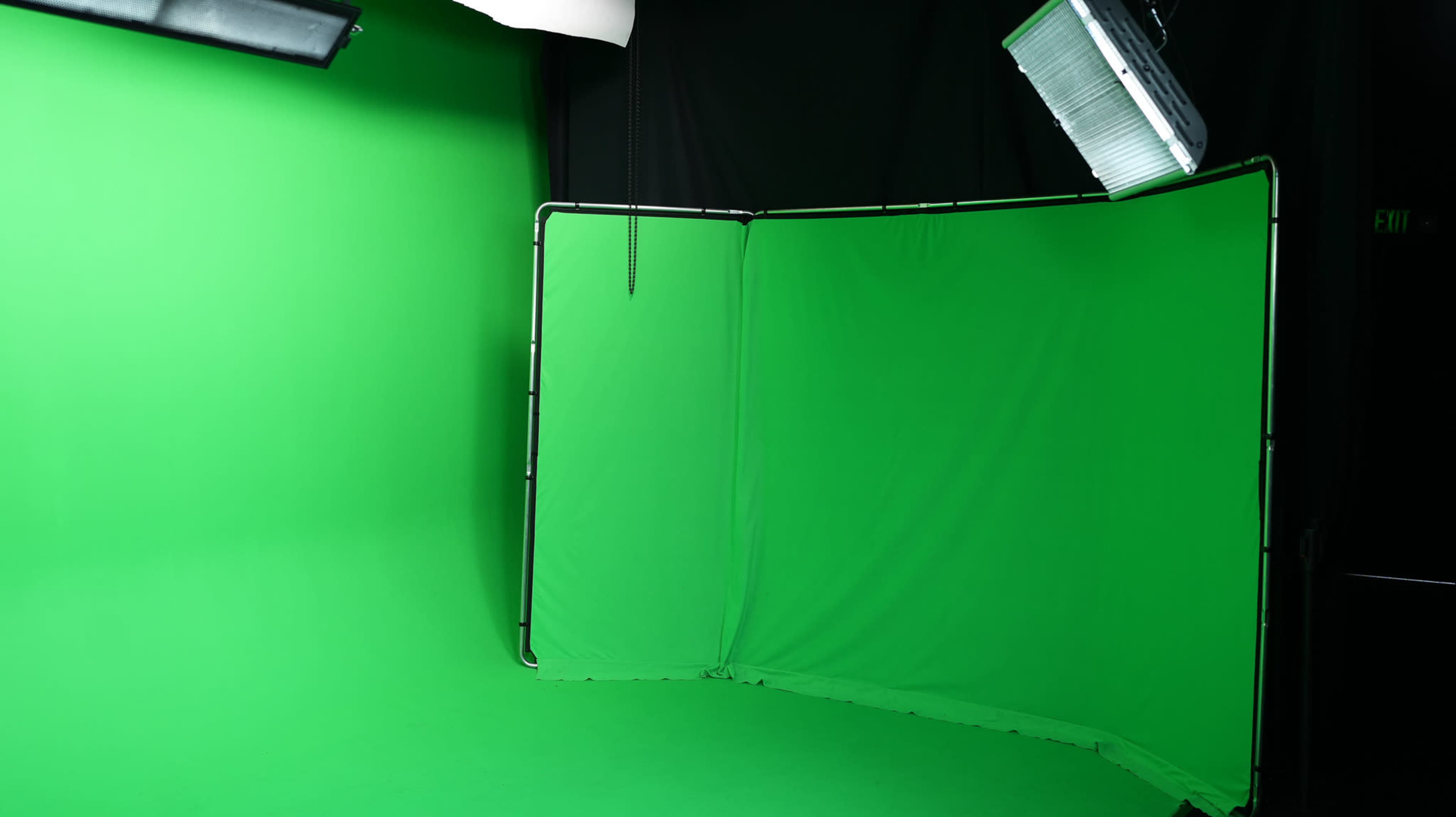 A green screen setup in a studio with lighting equipment.