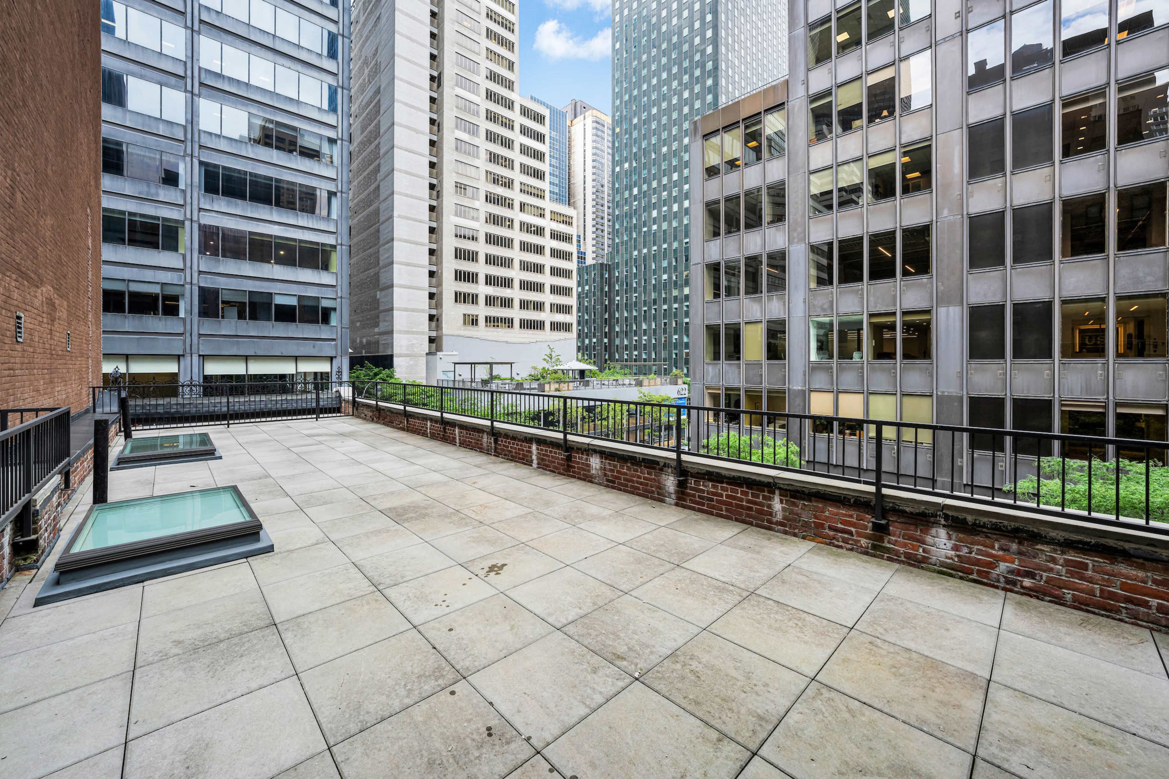 A rooftop terrace surrounded by tall buildings in an urban setting.