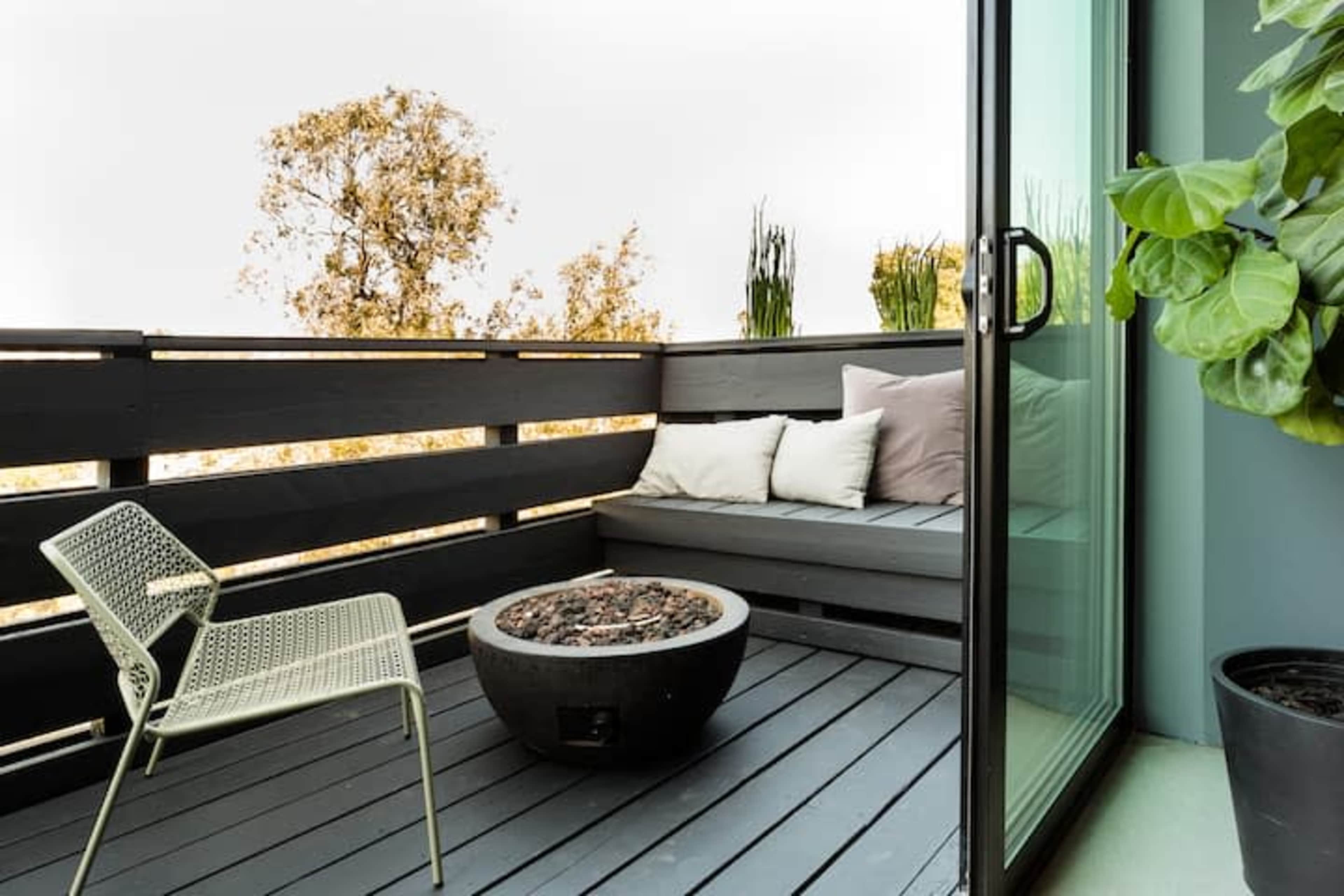 A small balcony features a circular fire pit surrounded by a seating area with cushions and a metal chair.