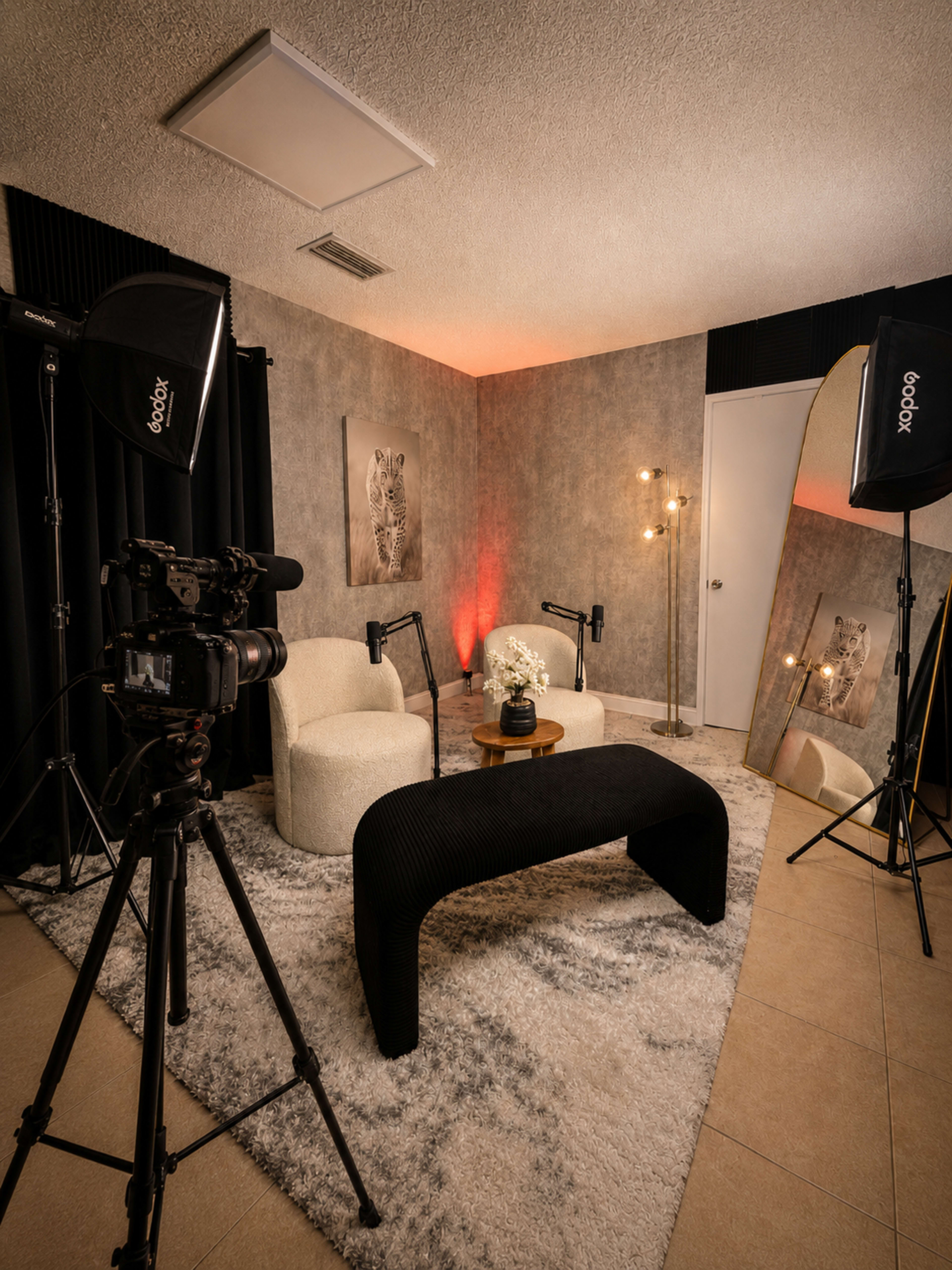 A photography studio setup features two chairs, a table with flowers, a large mirror, and lighting equipment.