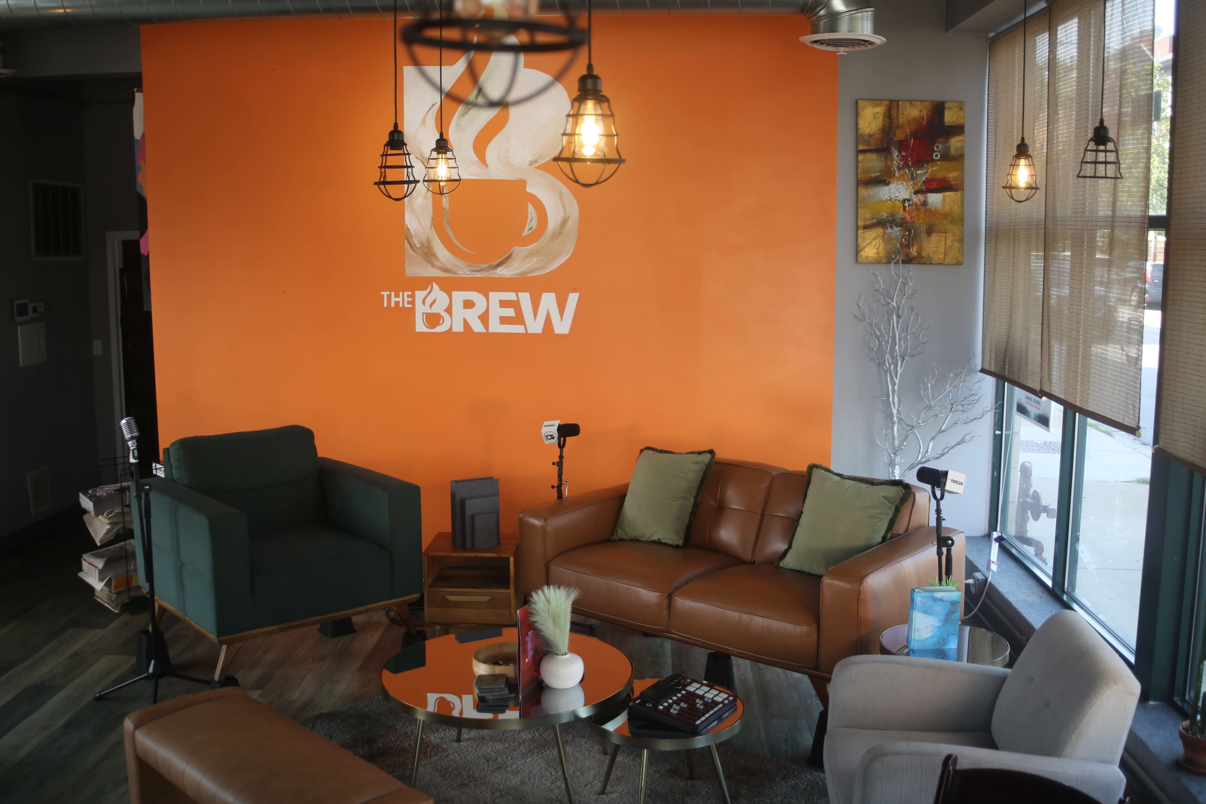 The image shows a cozy coffee shop interior with an orange accent wall, comfortable seating, and decorative lighting.