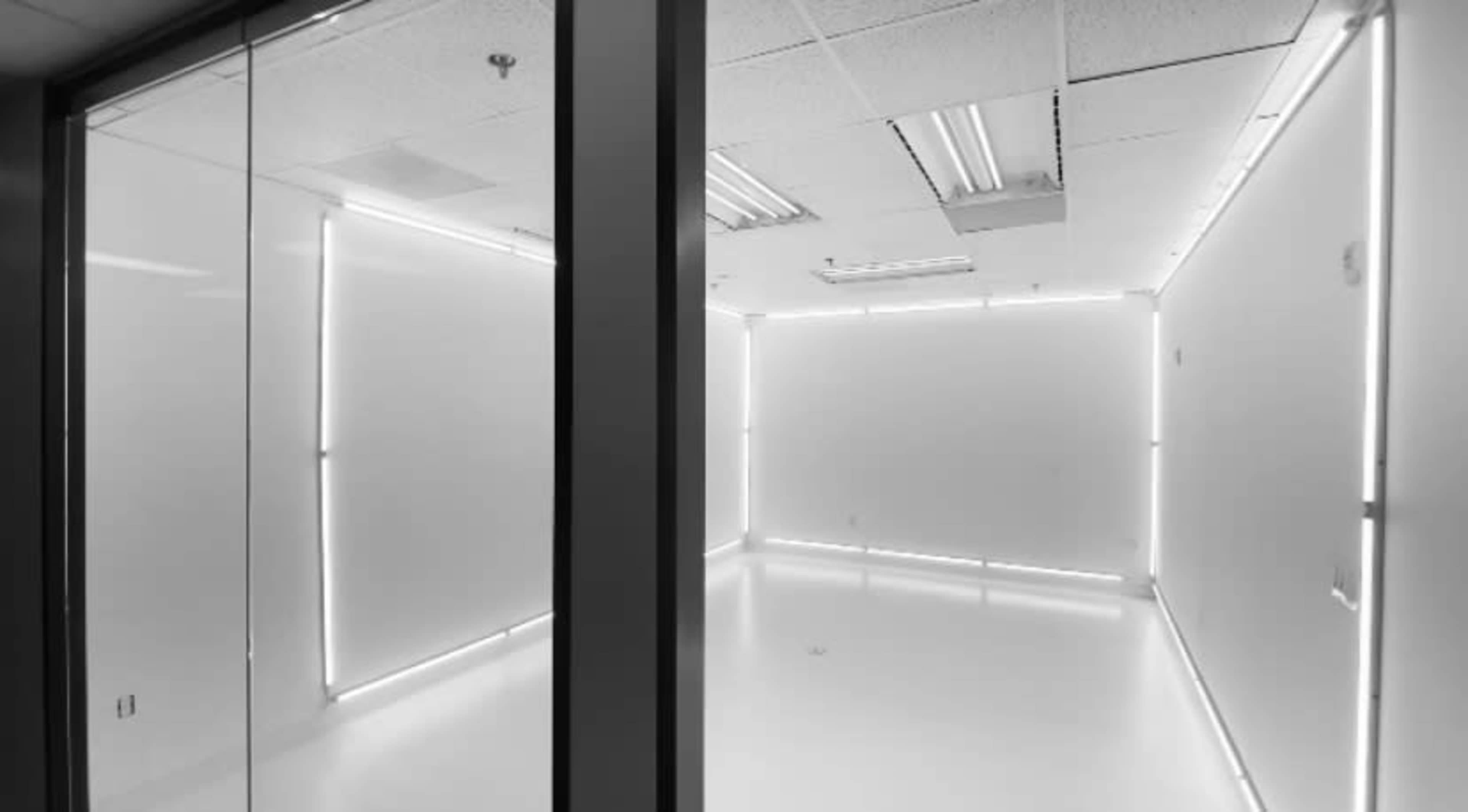 The image shows a minimalist, well-lit room with white walls and illuminated edges.