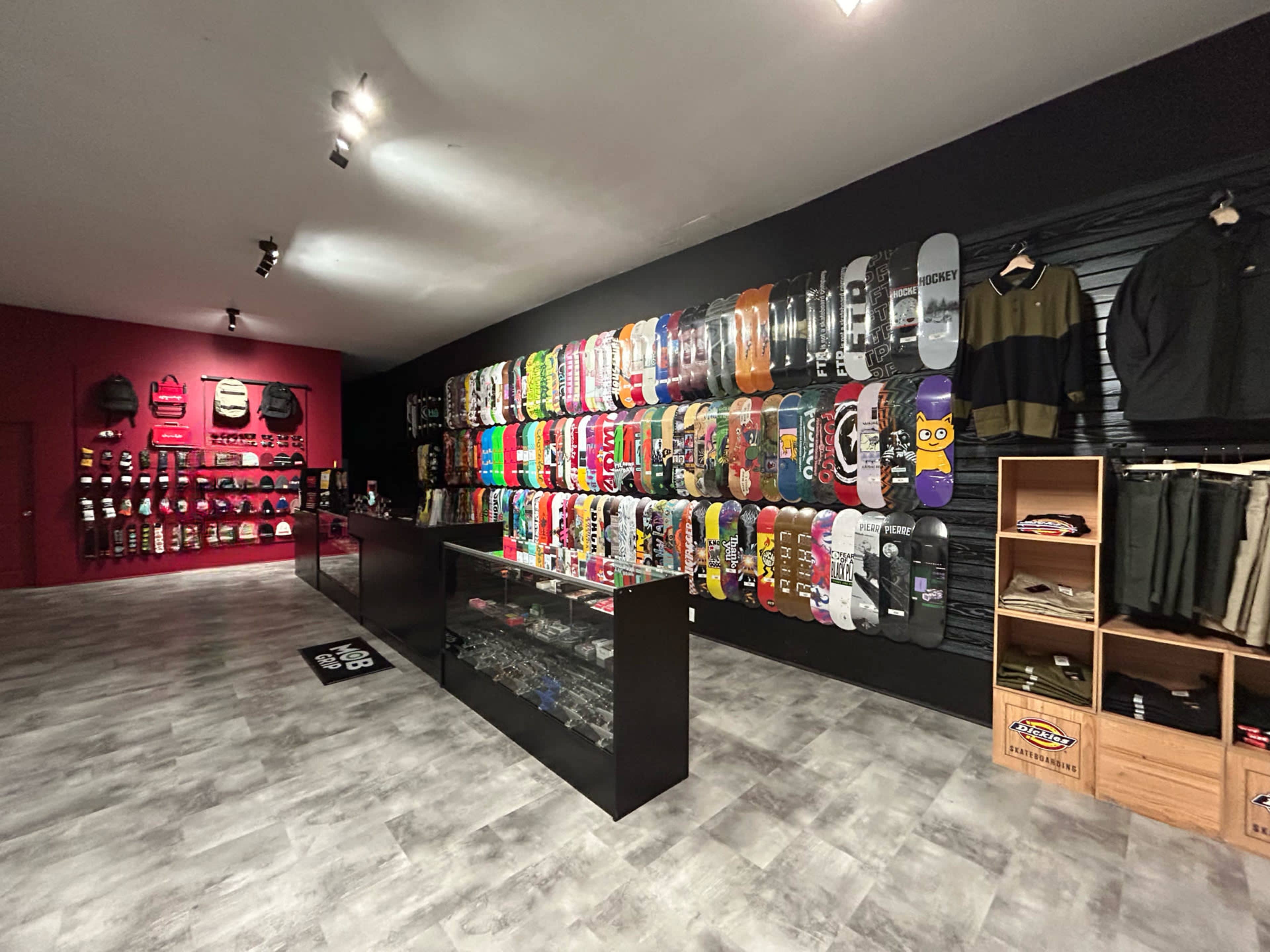 A skate shop interior with a wall of colorful skateboards displayed alongside apparel and accessories on shelves.