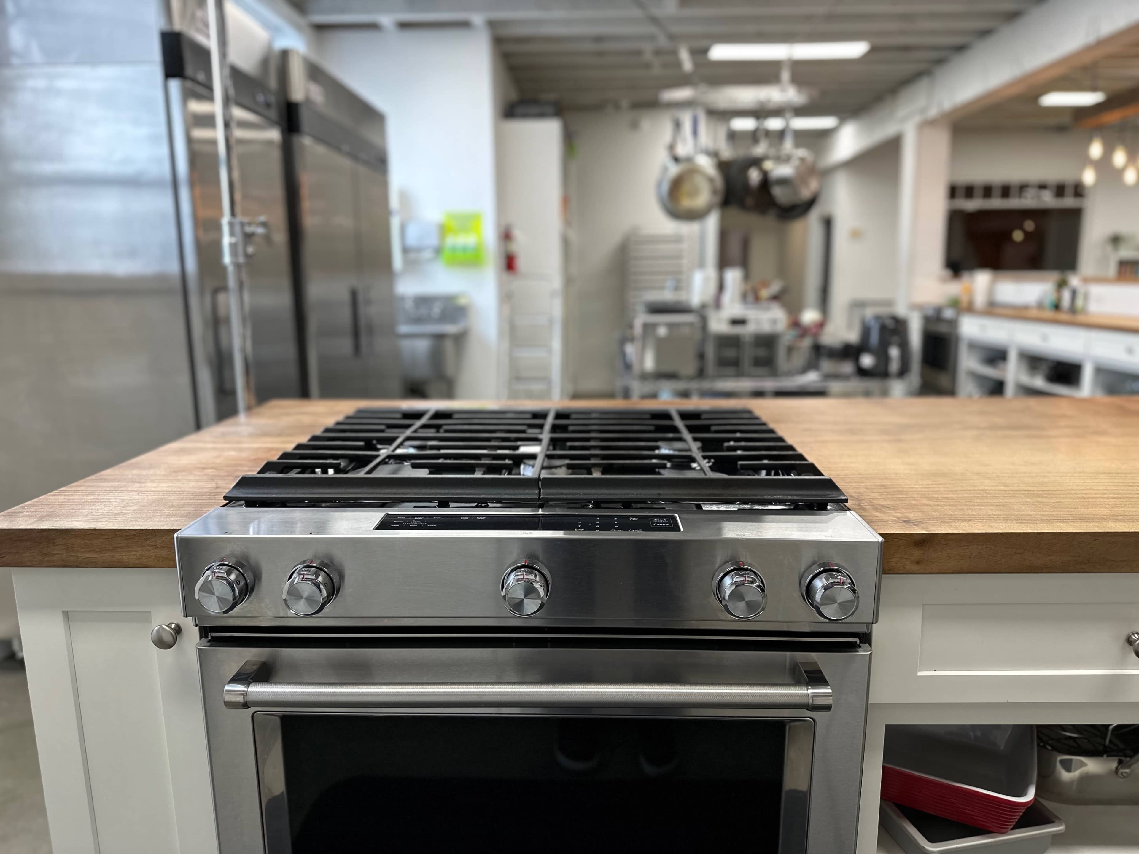 A stainless steel gas stove top on a wooden countertop in a modern kitchen.