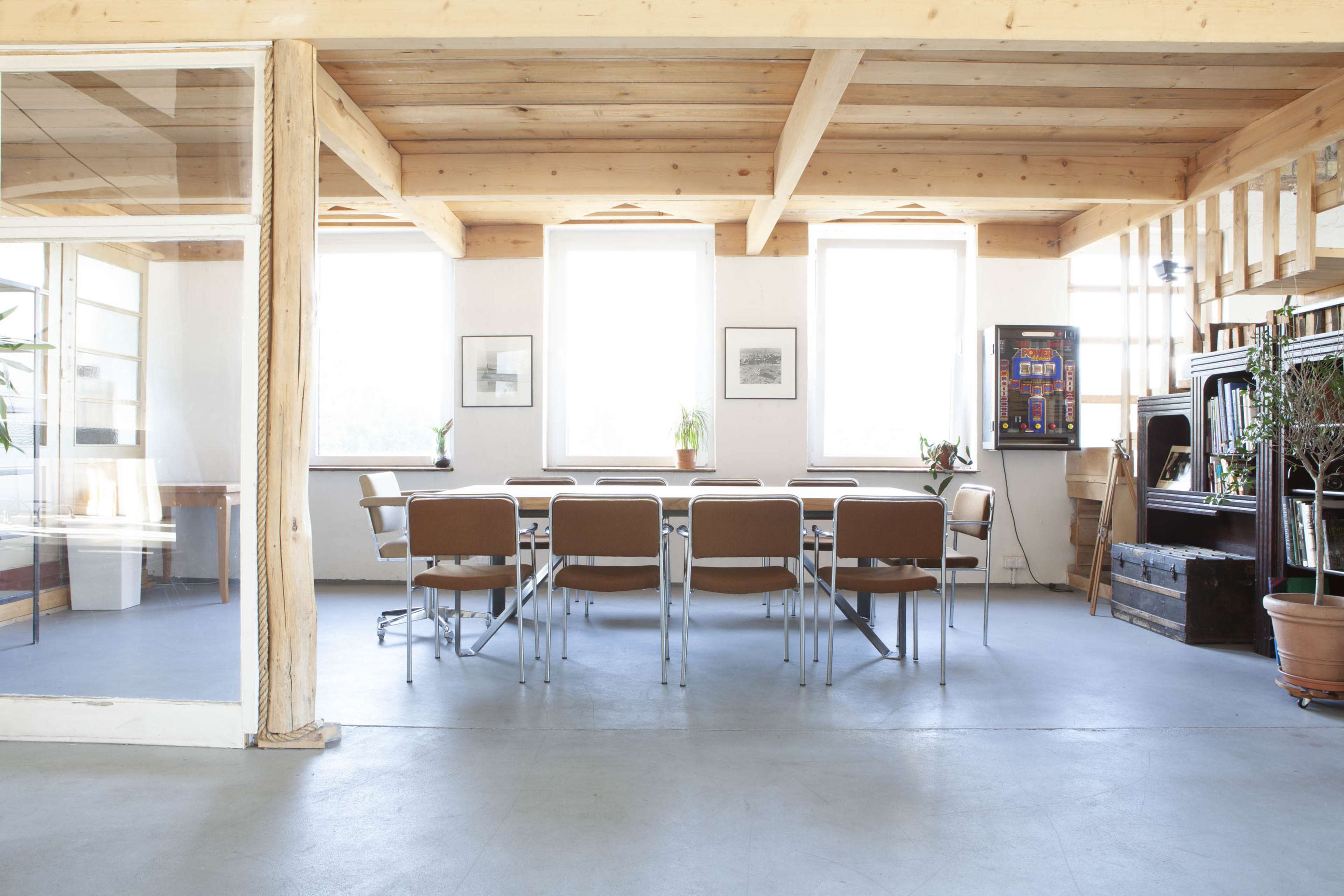A conference room features a long table surrounded by chairs, with large windows allowing natural light to illuminate the space.