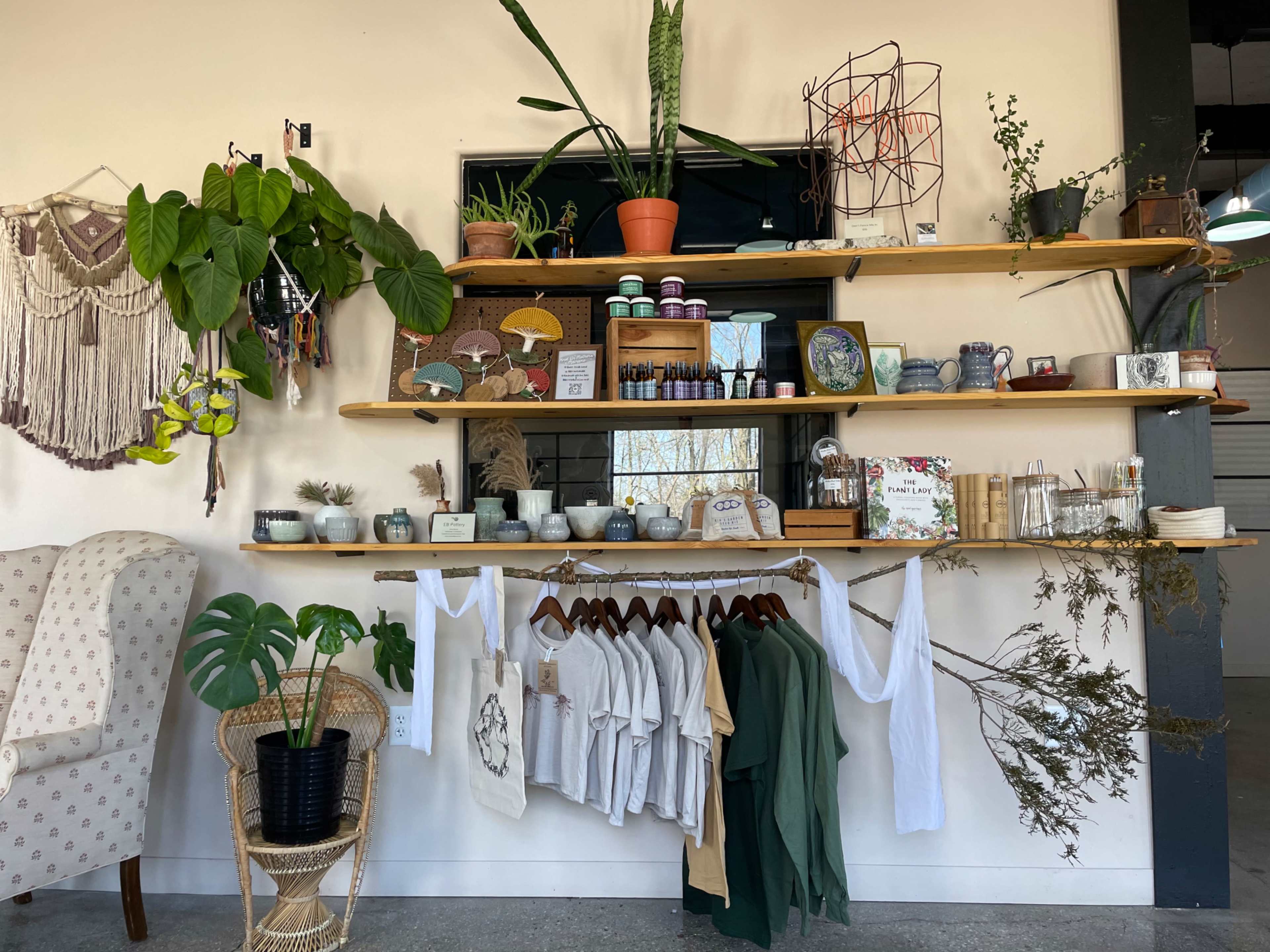 A wooden shelf displays various plants, decorative items, and clothing in a well-organized retail space.