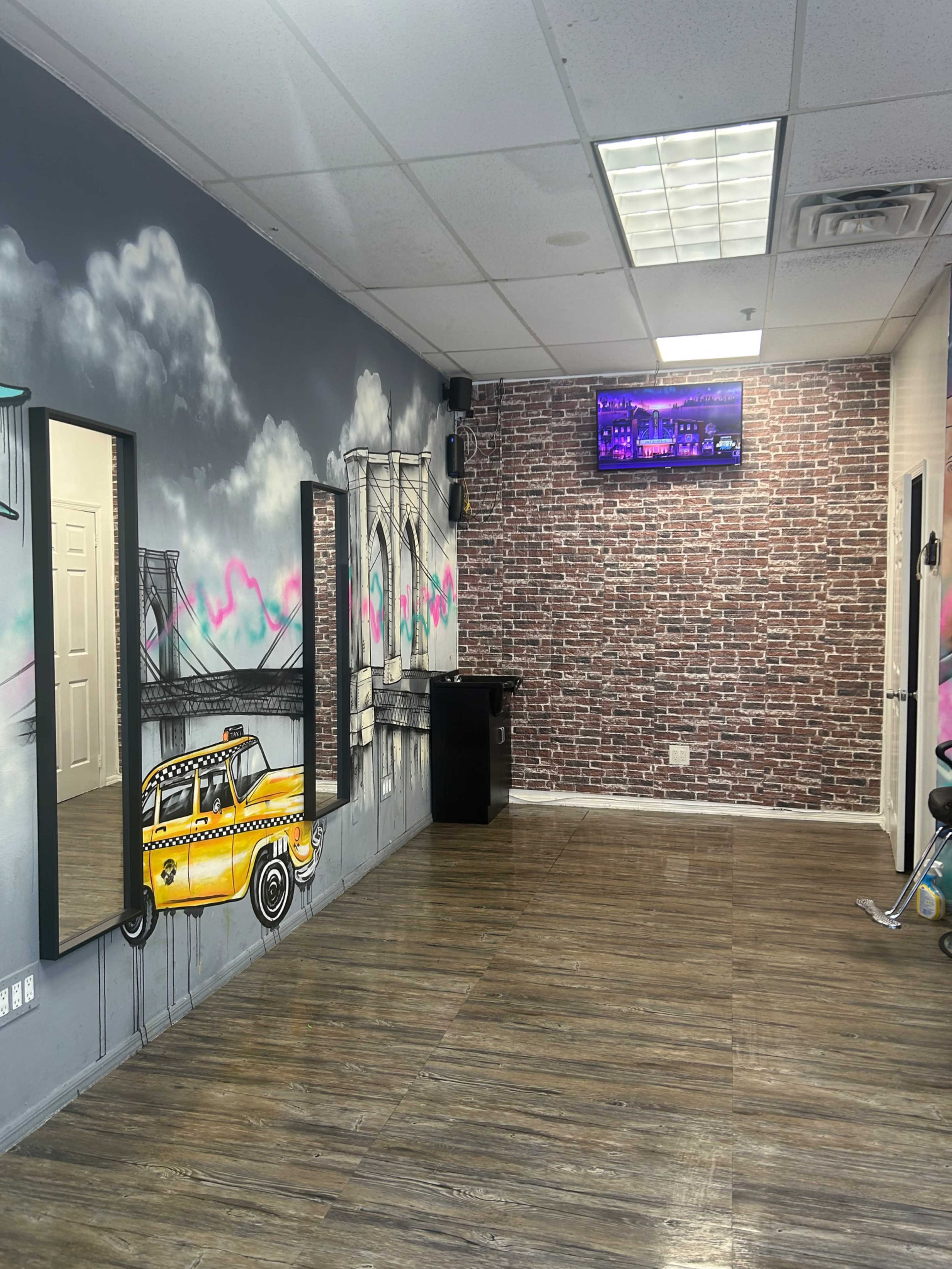 The image shows a salon interior with decorated walls featuring a mural of a bridge and a yellow taxi, along with mirrors and a television mounted in the corner.