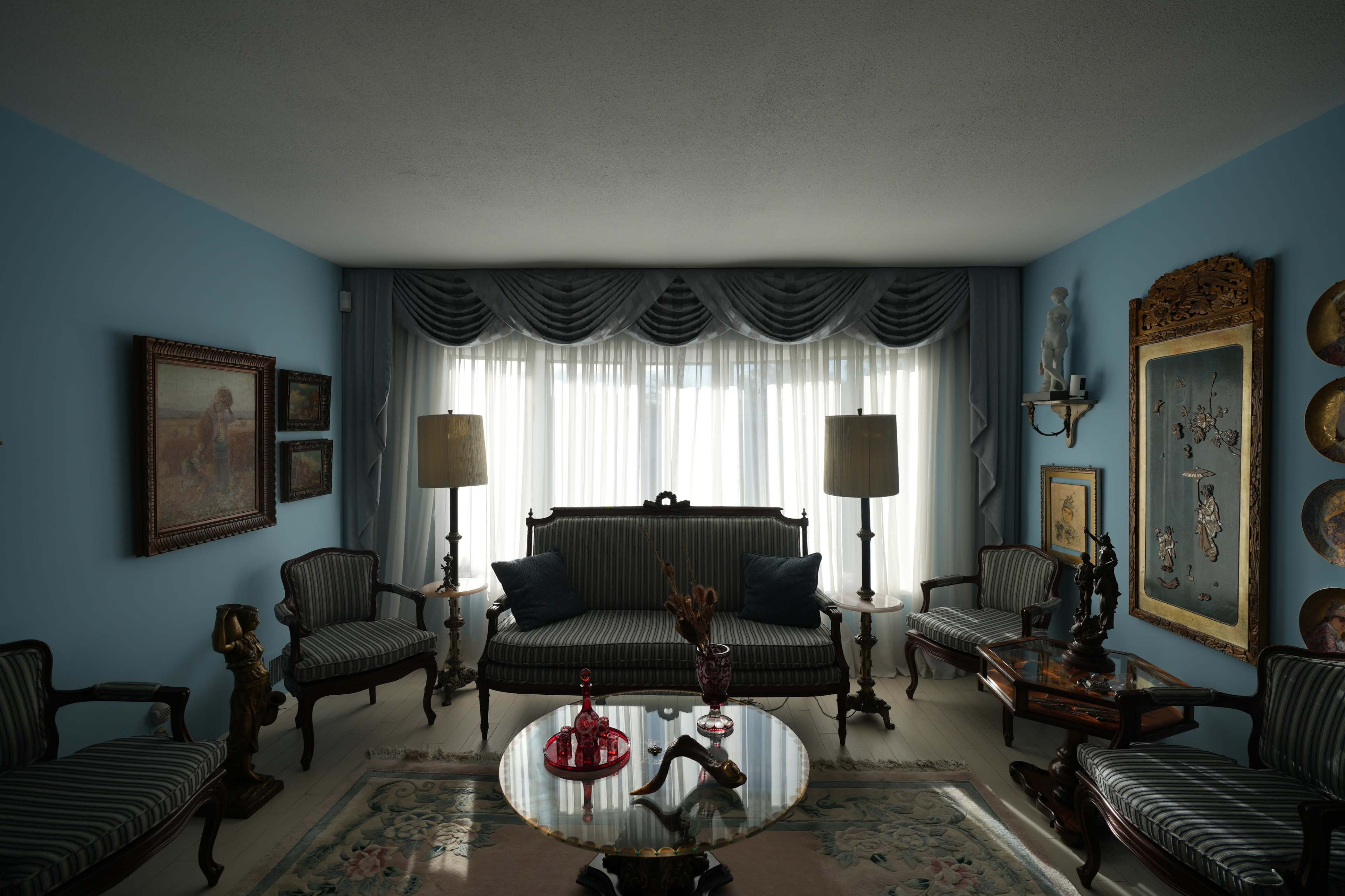 The image features a vintage living room with blue walls, a striped sofa, several chairs, and decorative artwork adorning the walls.