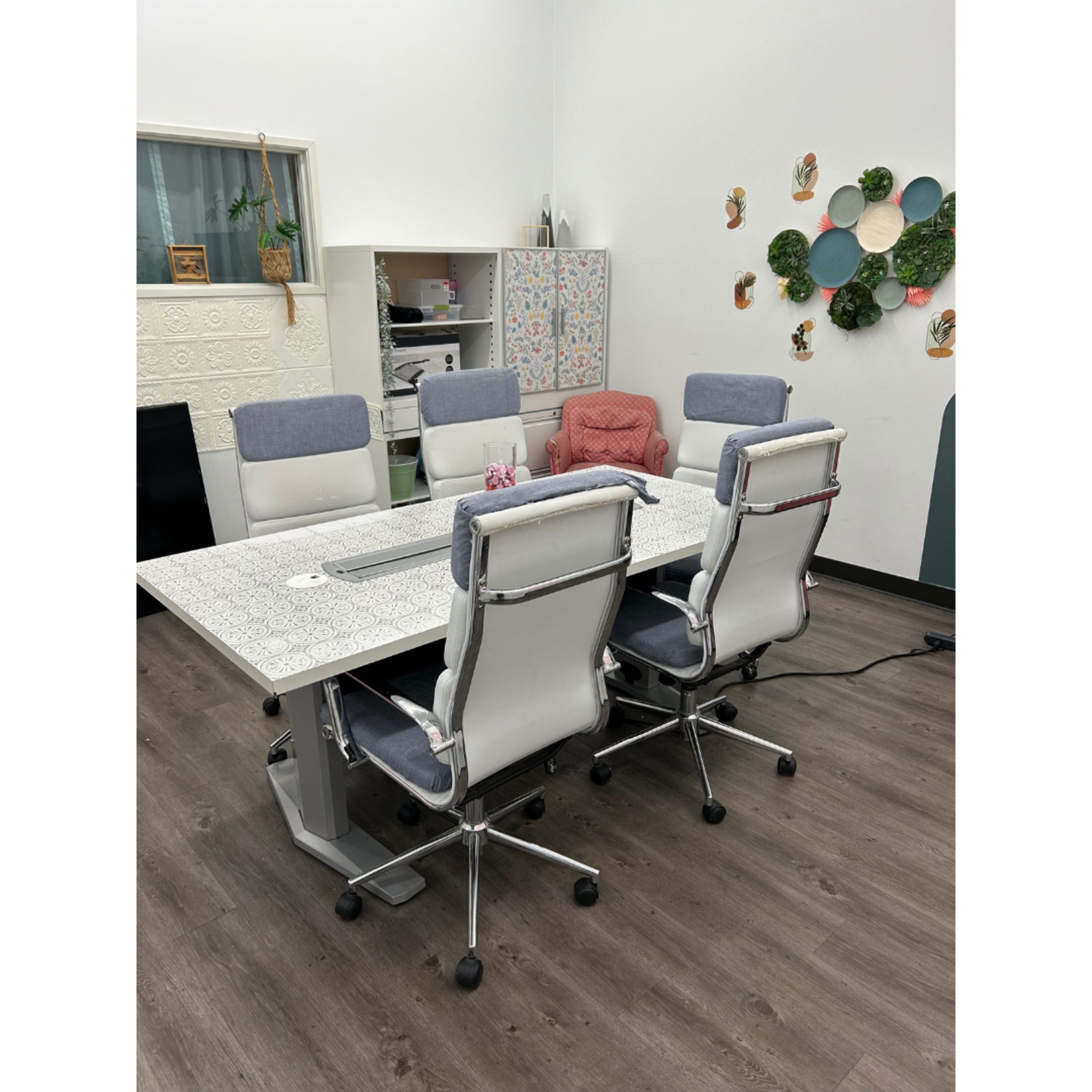 A modern conference room features a large table surrounded by several ergonomic chairs and a decorative wall with colorful circular accents.
