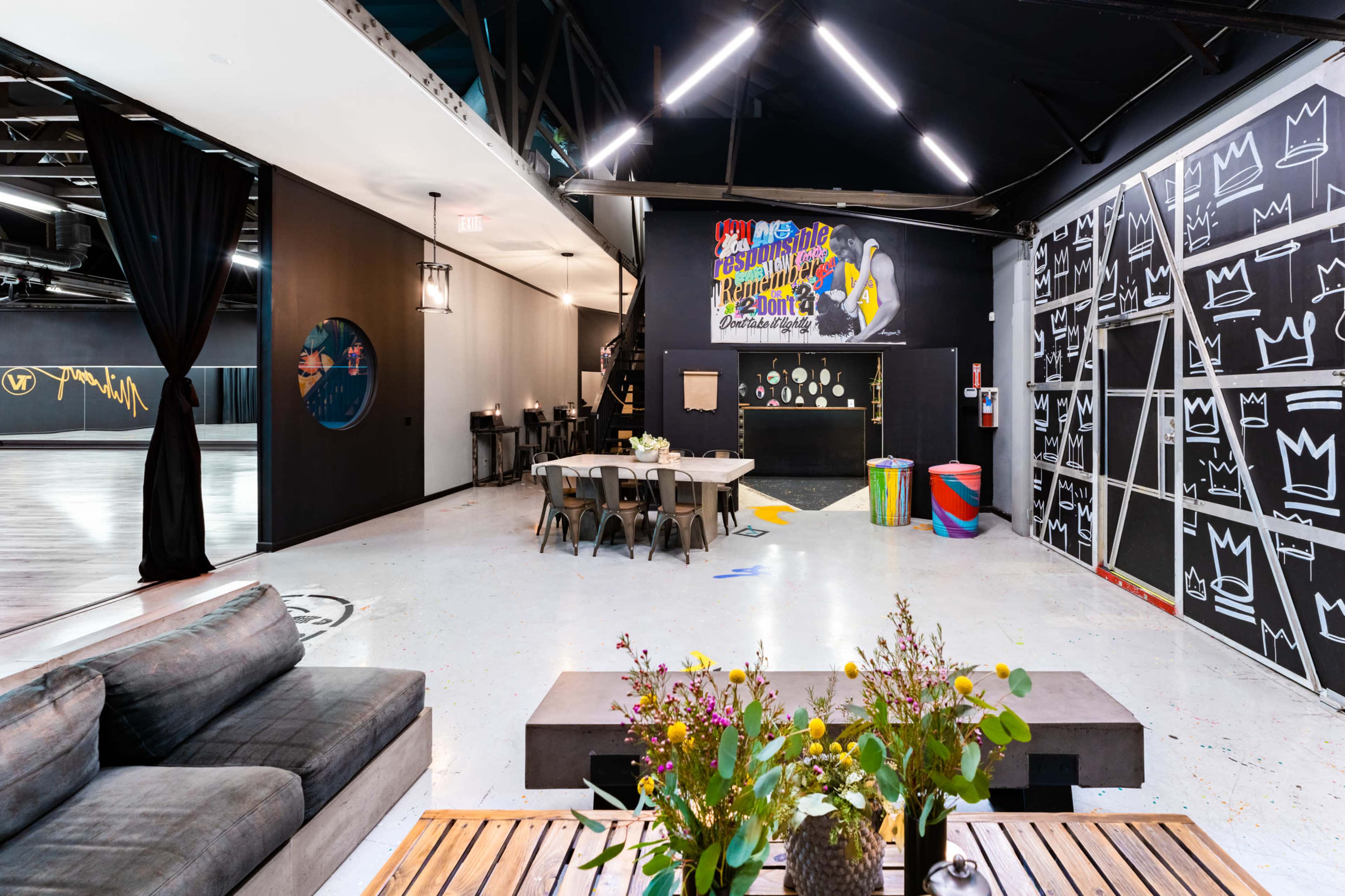 A spacious, modern interior with a seating area, a dining table, and walls featuring colorful artwork and graffiti.