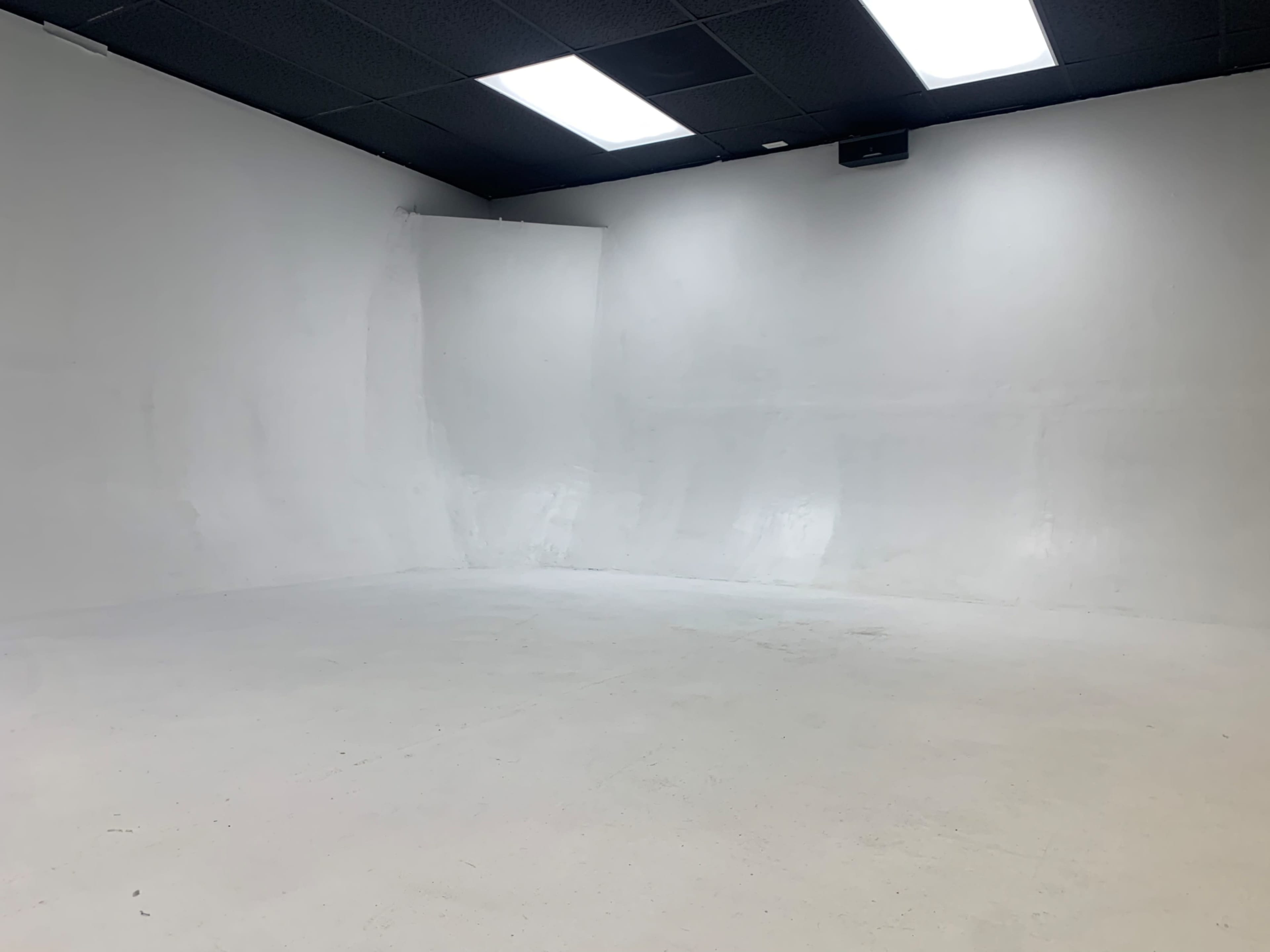 A large, empty studio space with white walls and a polished concrete floor.