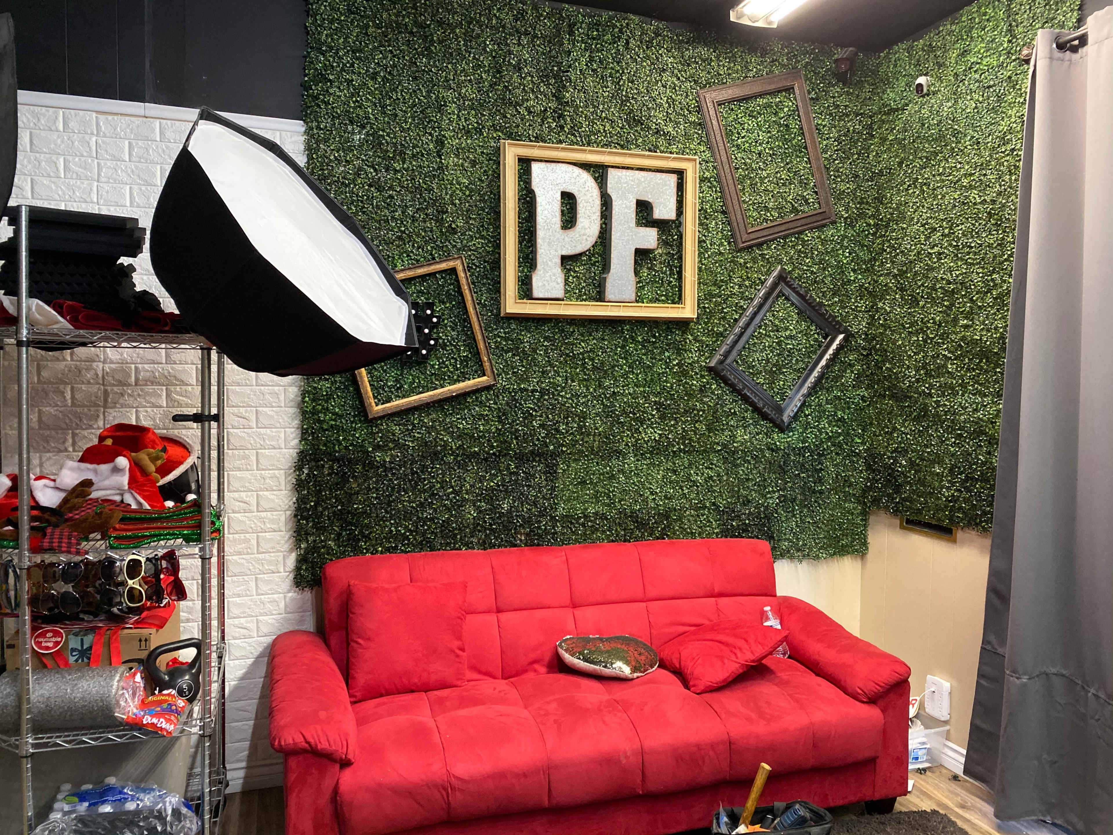 A red couch sits in front of a green, textured wall adorned with empty picture frames and a large "PF" display.
