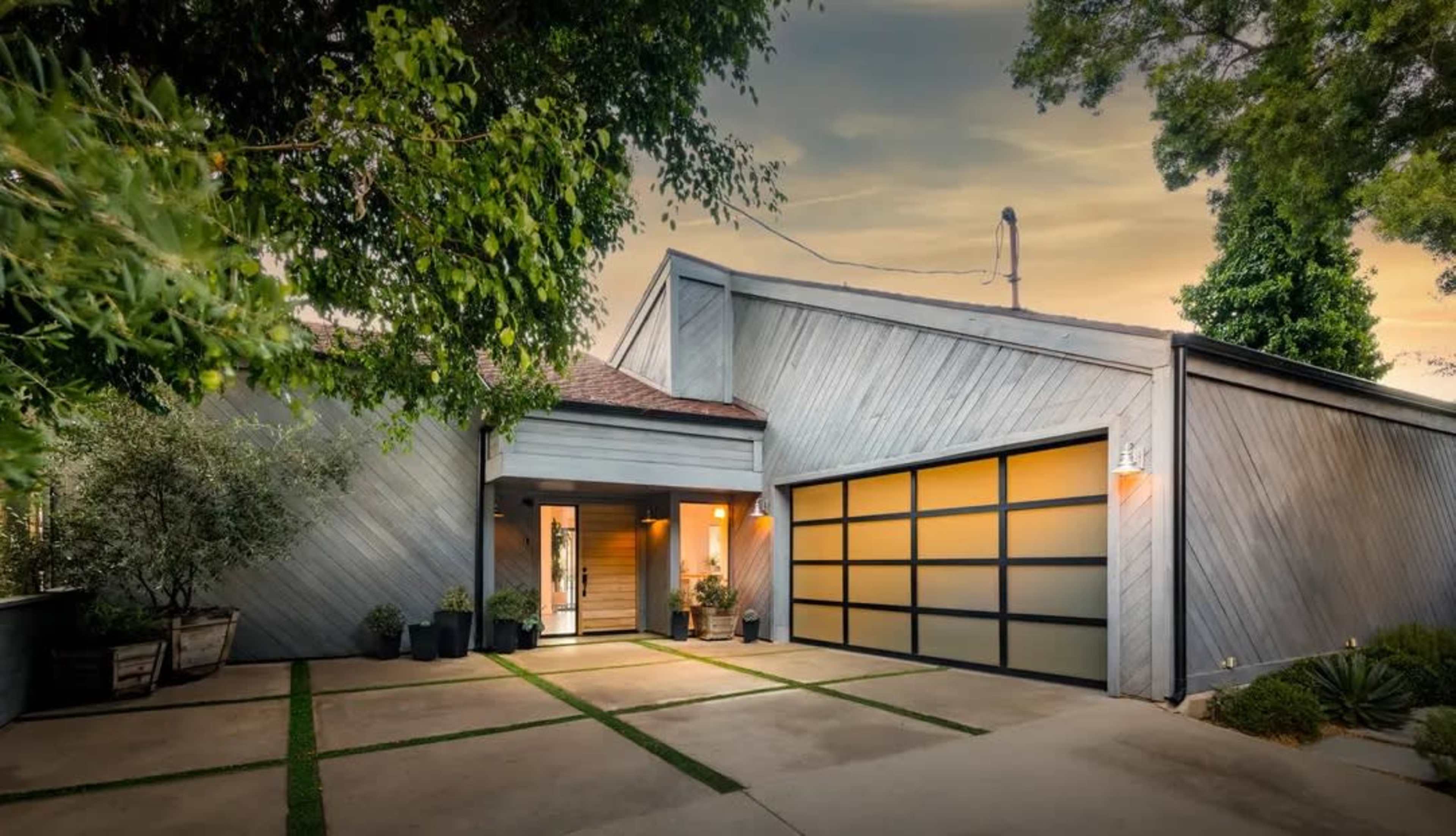 A modern single-story house features a gray exterior, a welcoming entrance, and a garage with glass door panels.