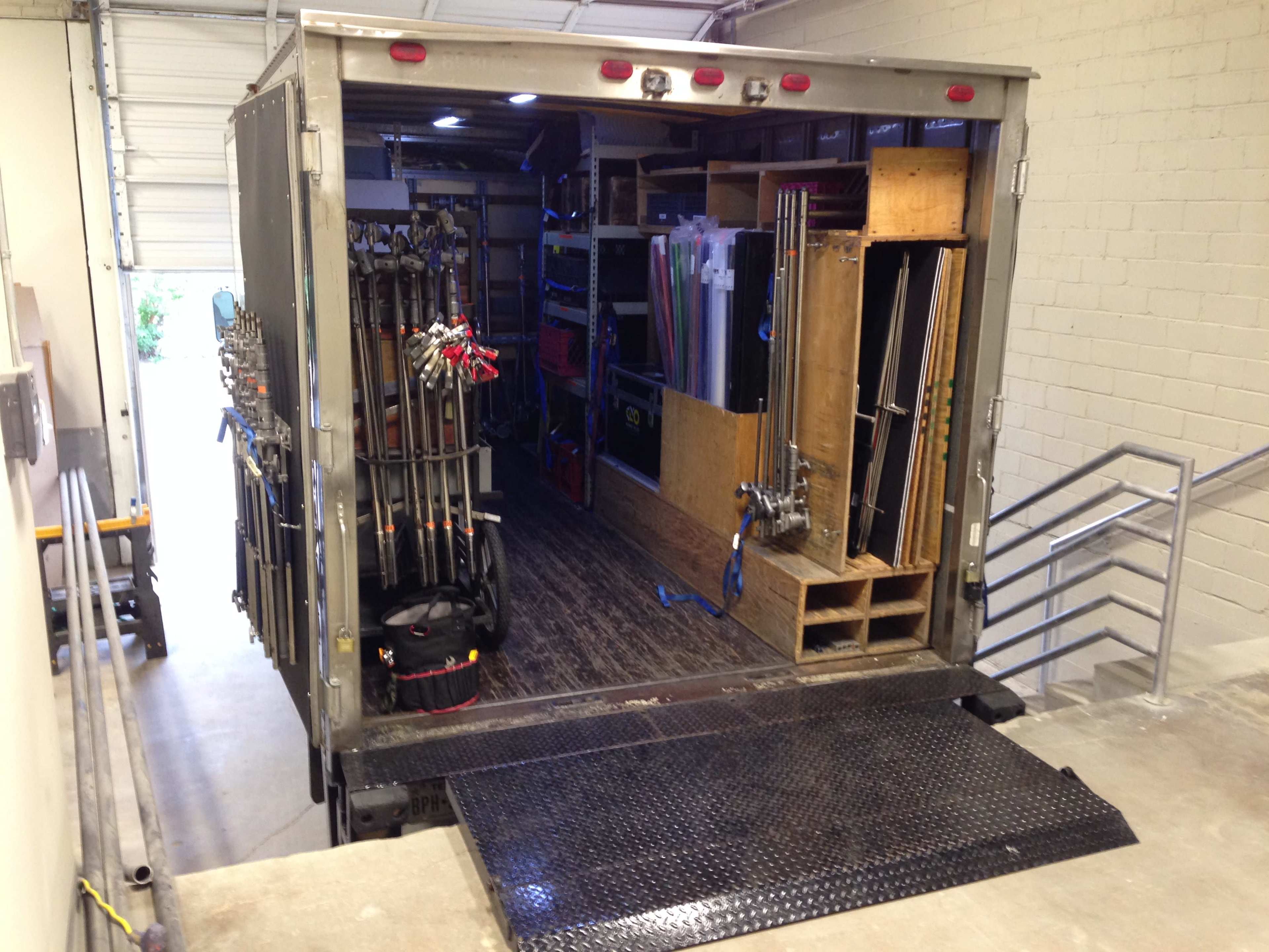 A large truck's cargo area is open, displaying organized shelves filled with various equipment and tools.