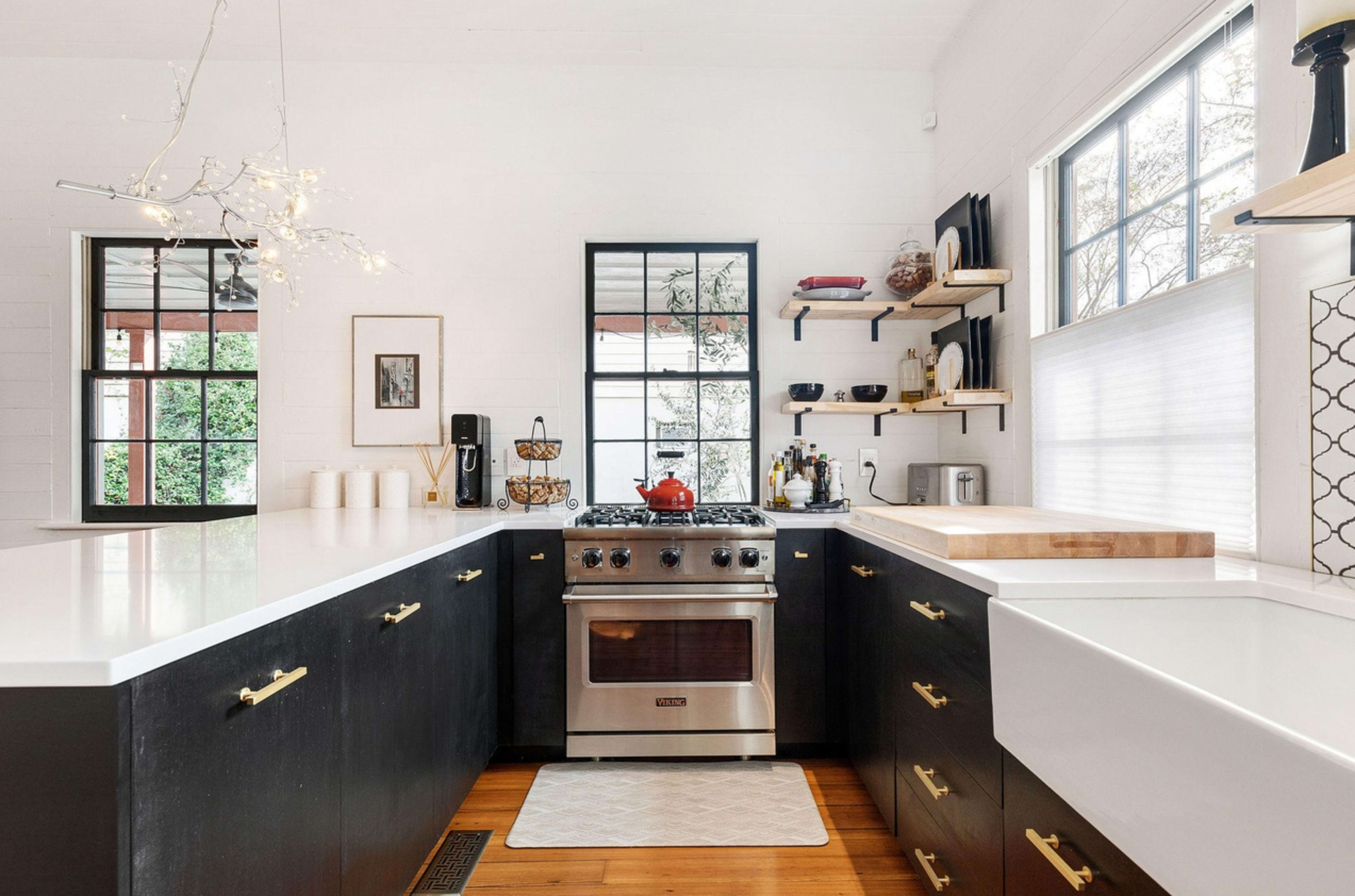 A modern kitchen features black cabinetry, a stainless steel stove, and wooden countertops with open shelving.